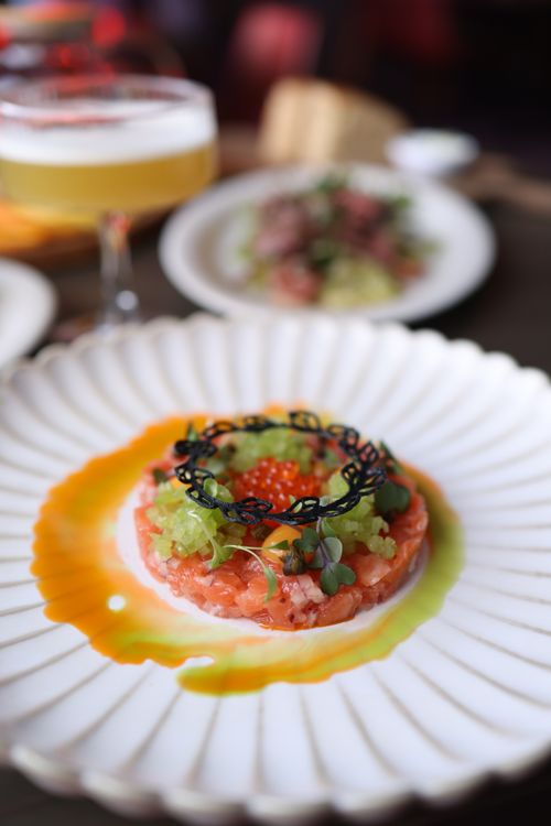 Free Delicious salmon tartare on a stylish plate, garnished with microgreens and black lace cracker. Stock Photo