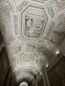 Explore the detailed and elegant frescoes adorning a corridor ceiling in Vatican City, capturing historic artistic craftsmanship.