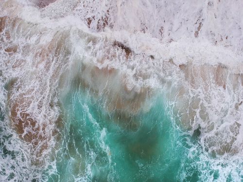 Free A stunning aerial view capturing ocean waves crashing with turquoise sea tones. Stock Photo