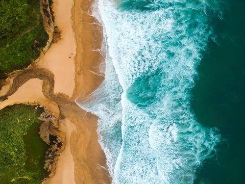 Free Drone shot of a beautiful sandy beach and ocean waves from above. Stock Photo
