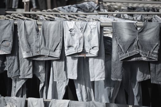 A collection of worn denim jeans hanging to dry on outdoor racks, creating a rustic and vintage vibe.