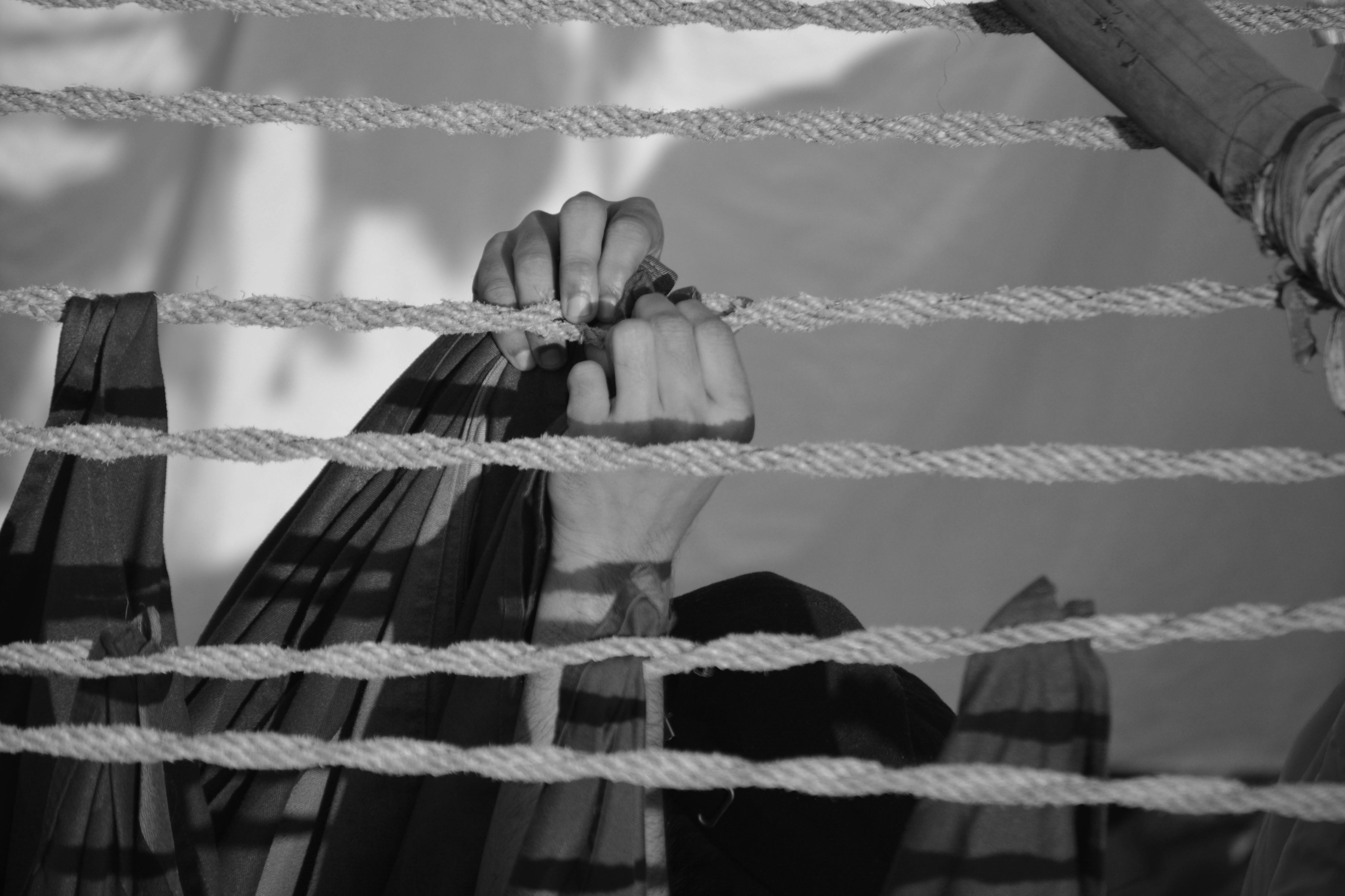Free Hands intricately securing ropes in a nautical setting with a monochrome aesthetic. Stock Photo