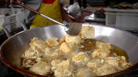 Fried tofu being prepared in a street market for a crispy snack.
