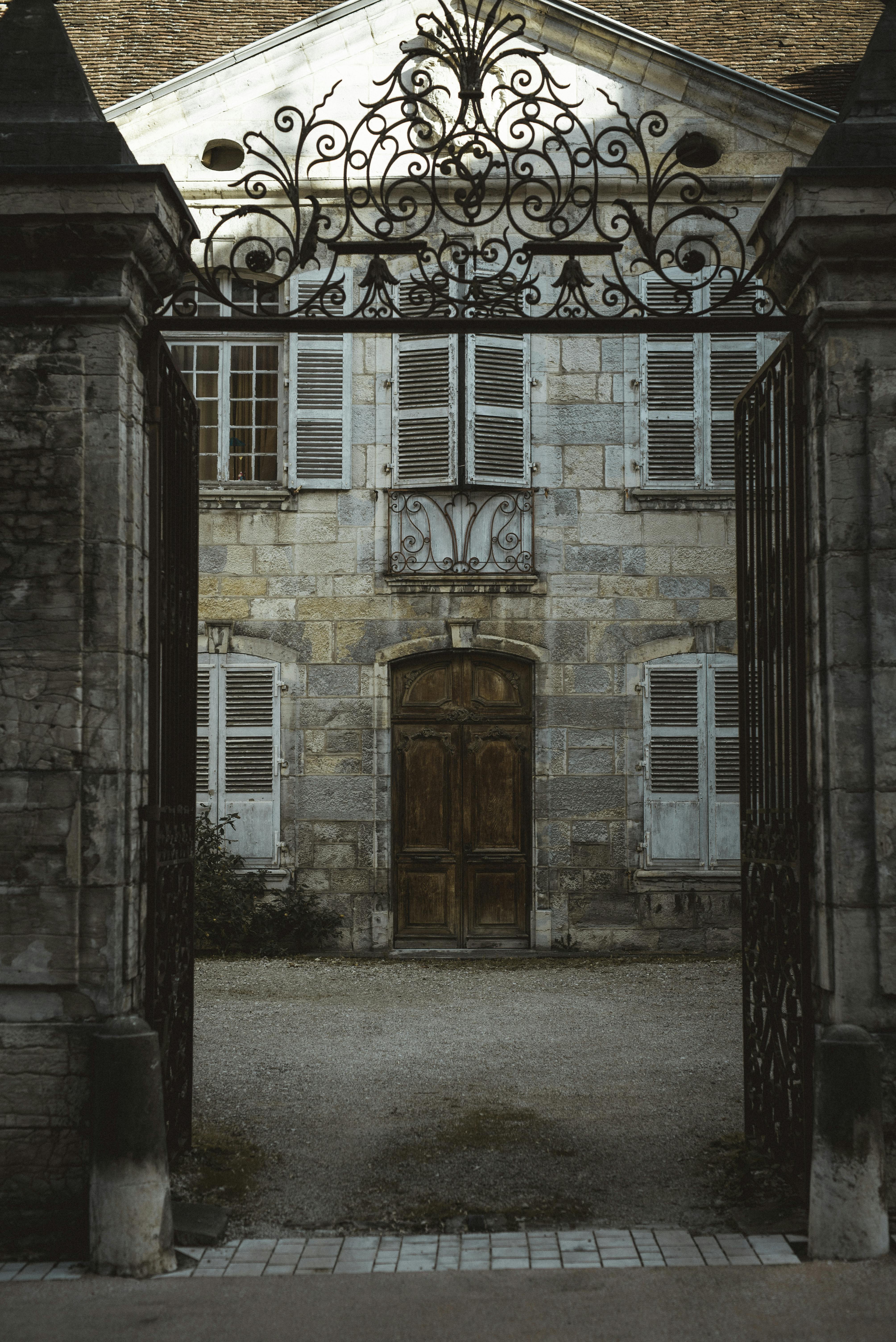 Δωρεάν Ένα μεγαλοπρεπές ιστορικό αρχοντικό που φαίνεται μέσα από μια περίτεχνη σιδερένια πύλη, αποπνέει διαχρονική γοητεία. Φωτογραφία από στοκ φωτογραφιών