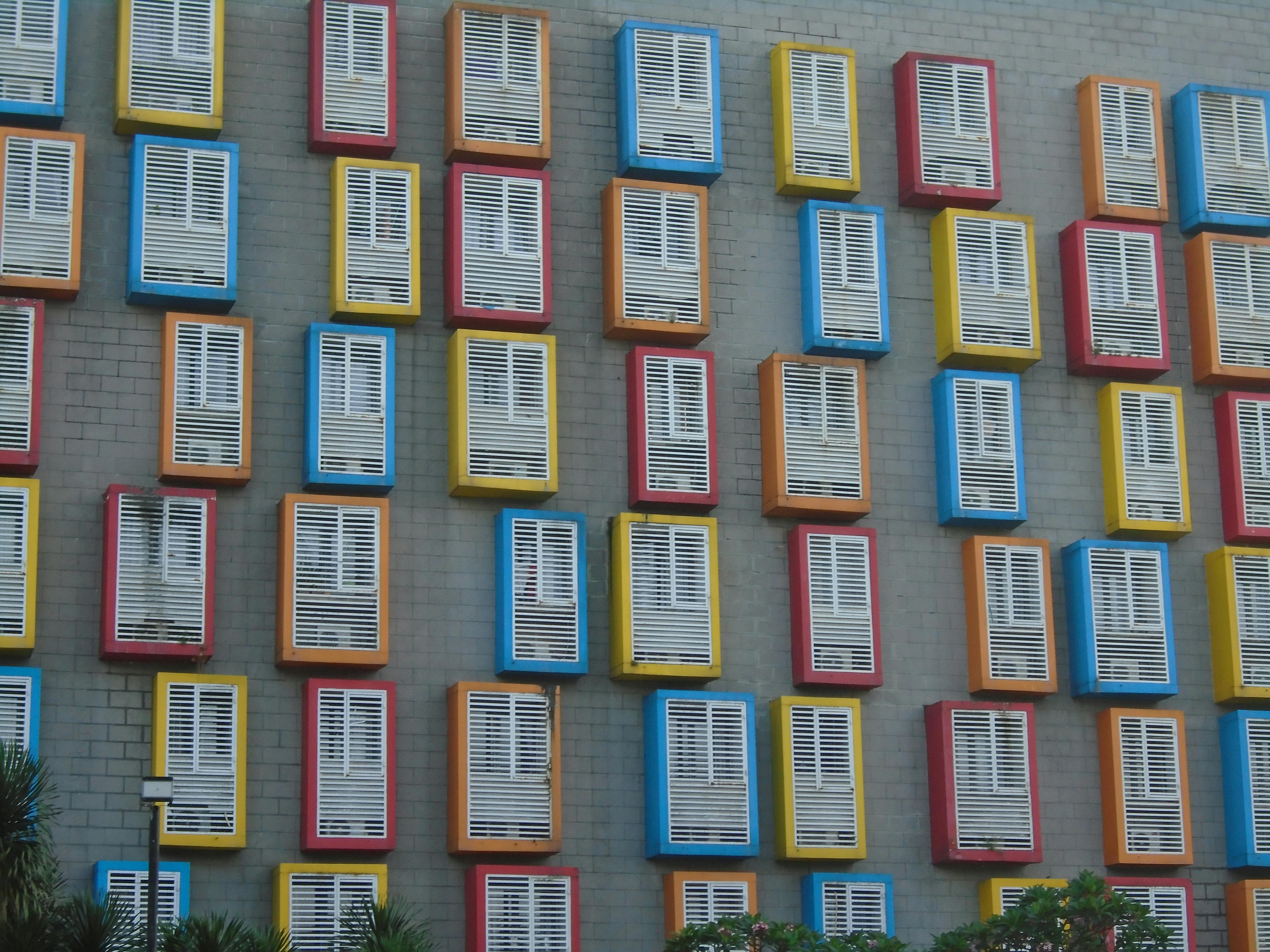 Gratuit Obloanele viu colorate de pe peretele unei clădiri urbane creează un model vizual izbitor. Fotografie de stoc