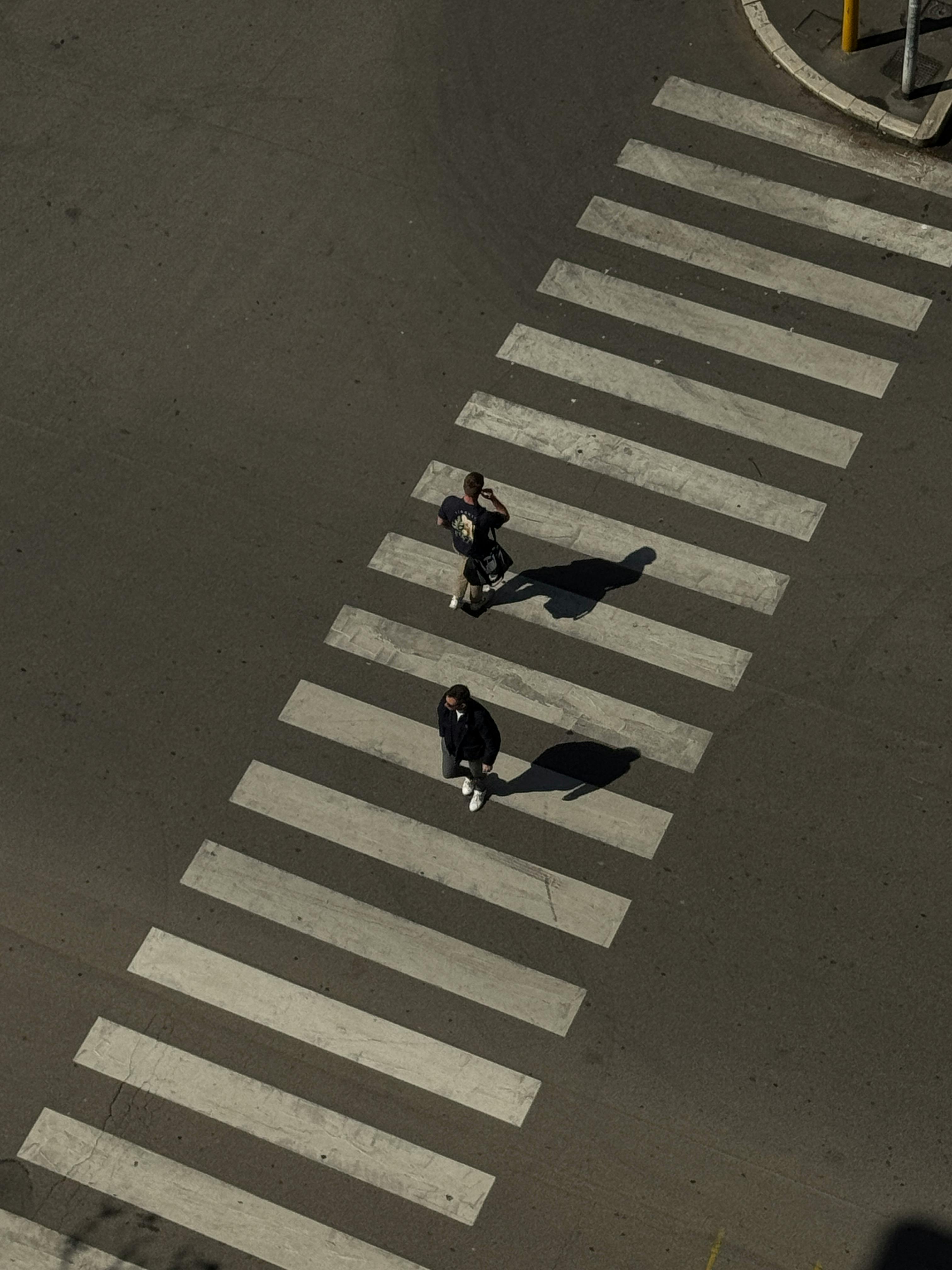 Gratuit Vue aérienne de deux adultes traversant un passage piéton par une journée ensoleillée en Italie. Photos