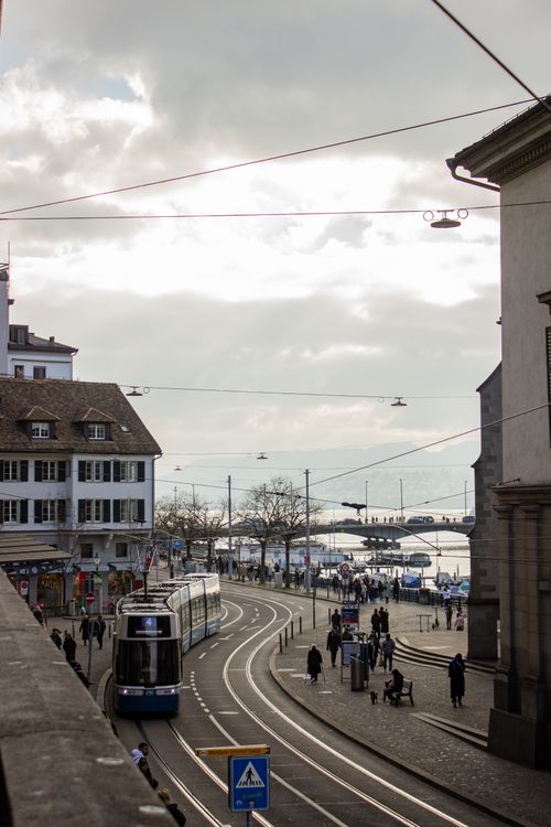 Free A scenic view of a tram near Lake Zurich with pedestrians walking in the city, capturing daily life in Switzerland. Stock Photo