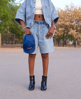 Stylish denim outfit with cap and boots outdoors in casual street fashion.