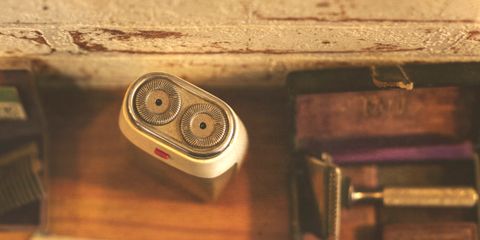 A twin-head electric razor on a warm wooden shelf