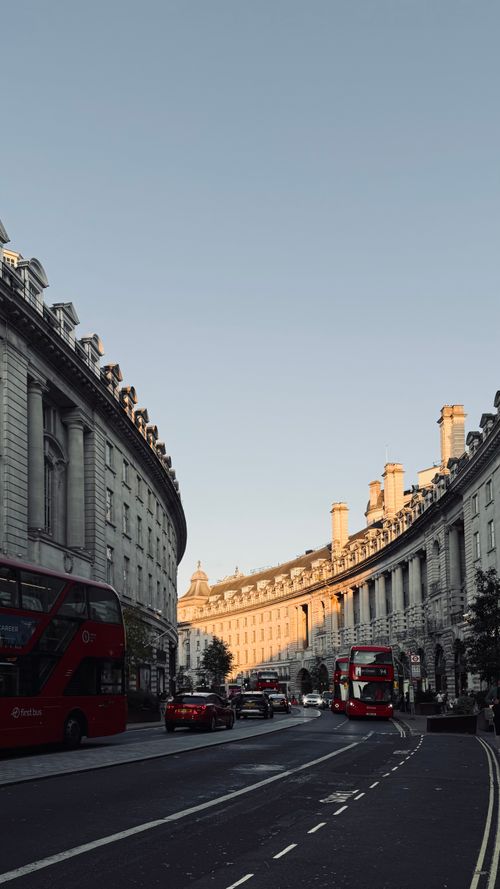 Free Regent Street in London featuring iconic red buses under a clear sky. Stock Photo