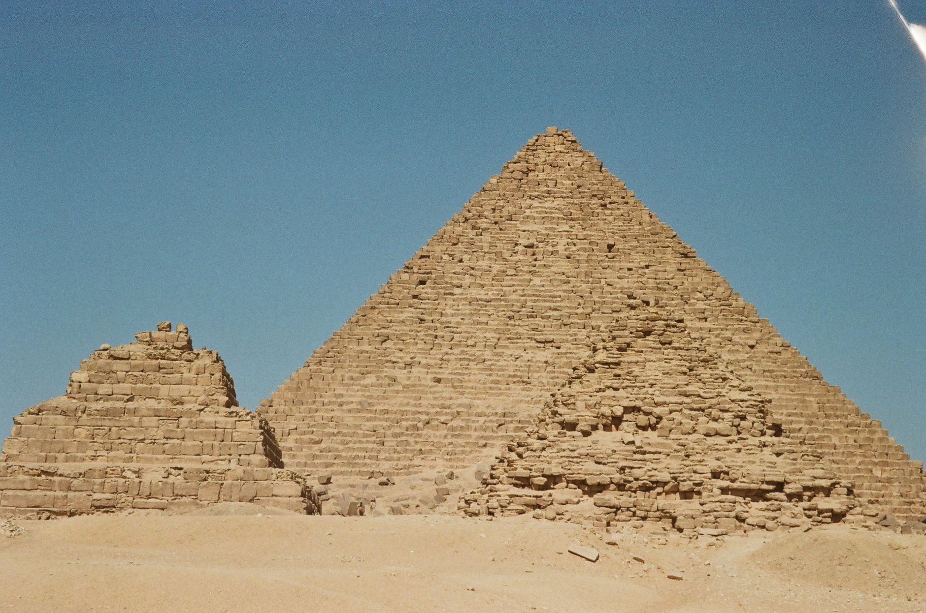 Discover the iconic pyramids of Giza, showcasing ancient Egyptian architecture against a clear blue sky.
