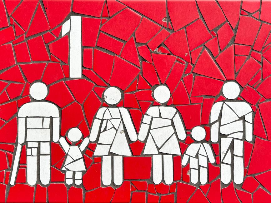 Mosaico colorido que representa a una familia sobre un fondo rojo vibrante, simbolizando la unidad y la diversidad.