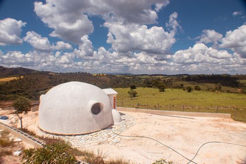 Free A unique dome-shaped house situated in a vast countryside under a vibrant sky. Stock Photo