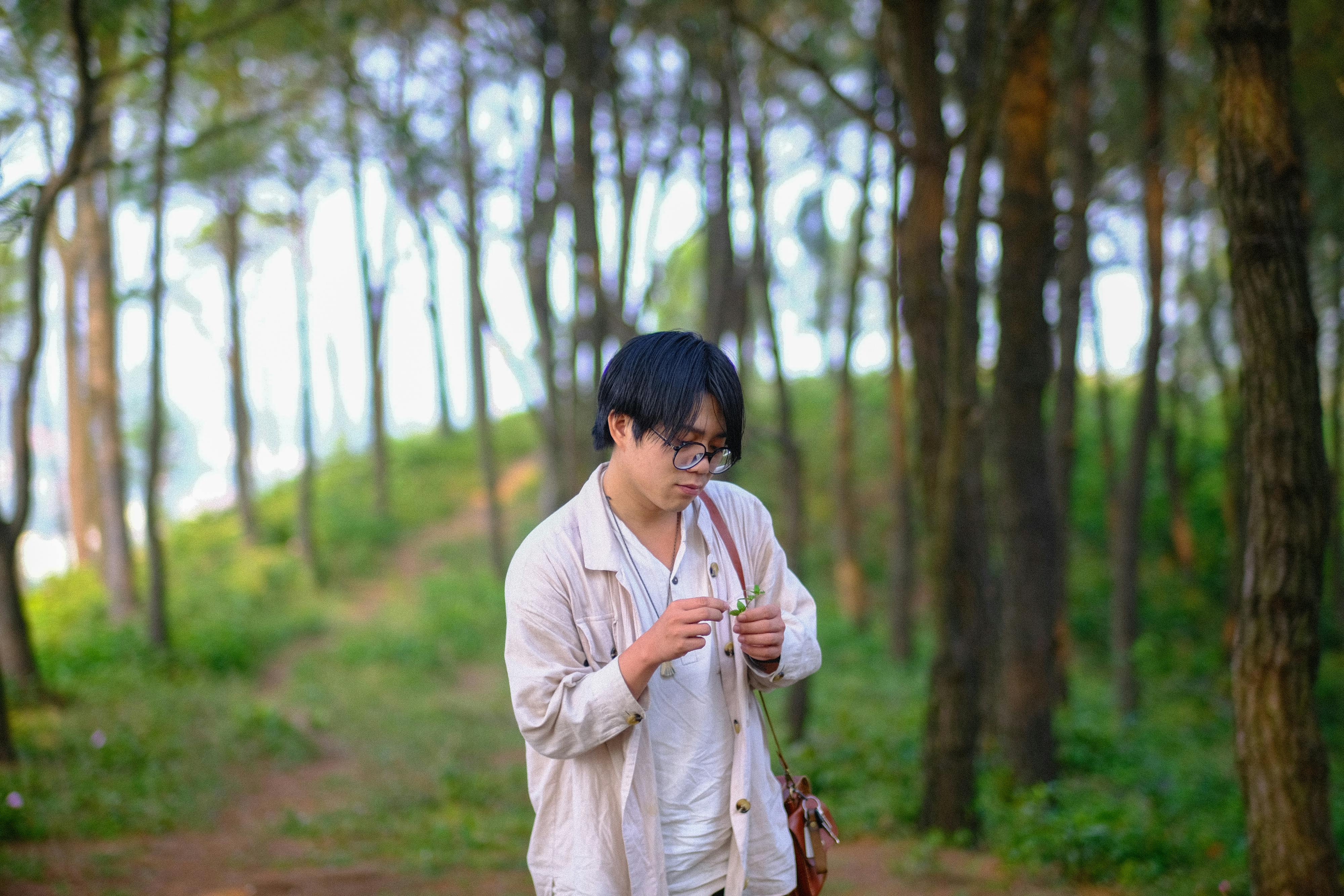 Kostenlos Eine Person erkundet die Natur in einem ruhigen Wald in Hue, Vietnam, und zeigt dabei ihren persönlichen Stil und ihre Gelassenheit. Stock-Foto