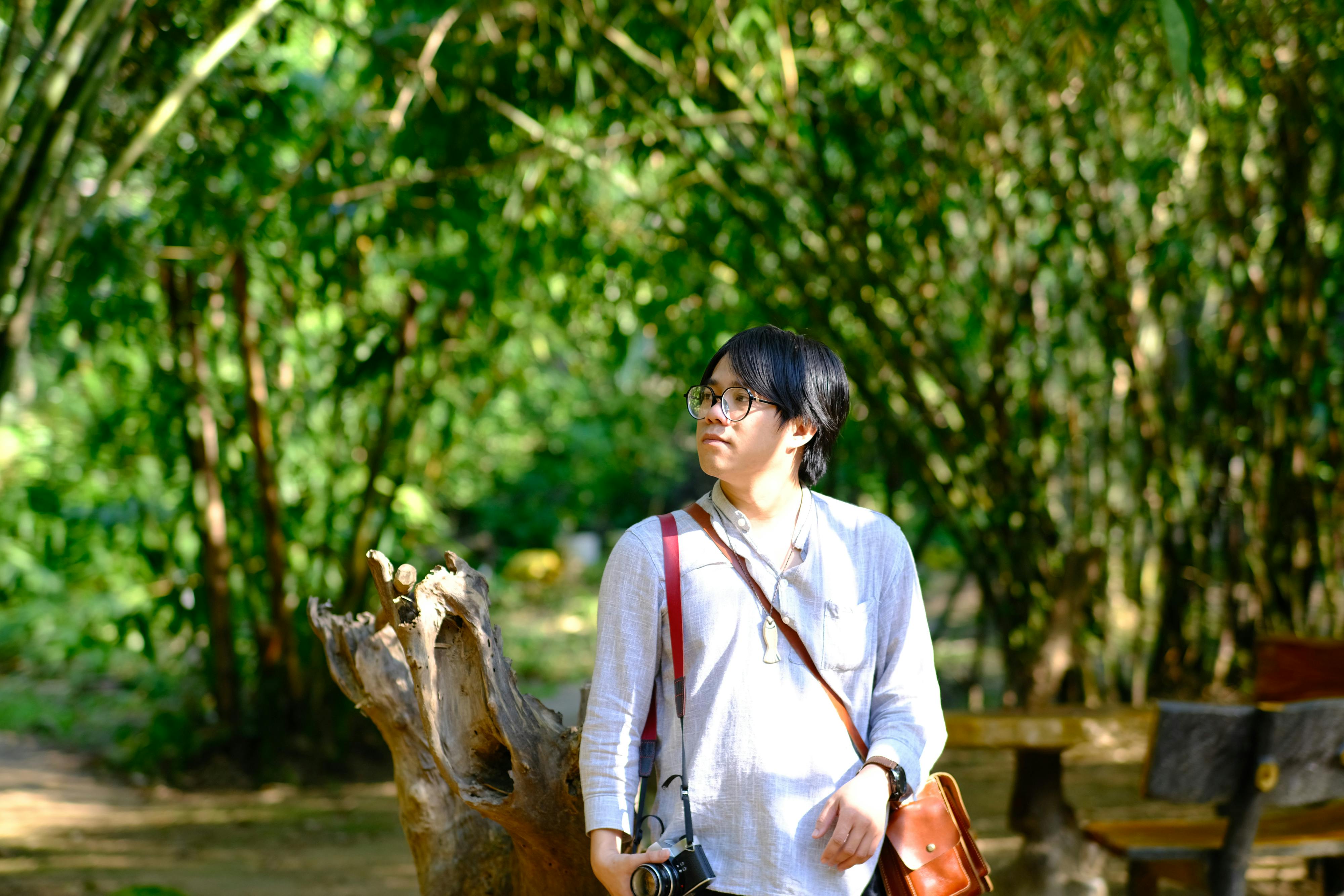 bezplatná Mladý dospělý prozkoumává pulzující zahradu v Hue ve Vietnamu a zachycuje přírodu fotoaparátem. Základová fotografie