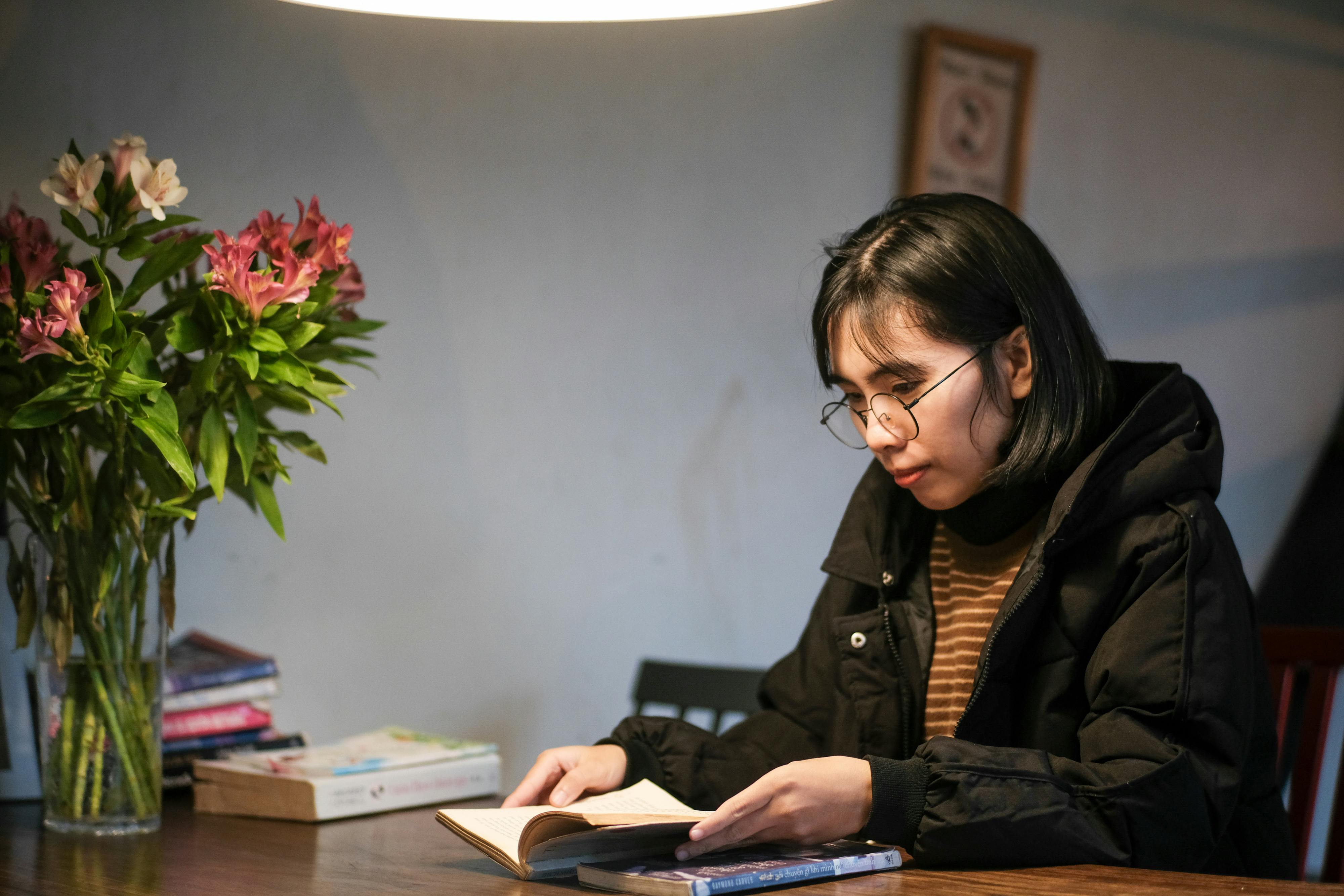 無料 ベトナムのフエにある居心地の良いカフェで本を読む若い女性。 写真素材