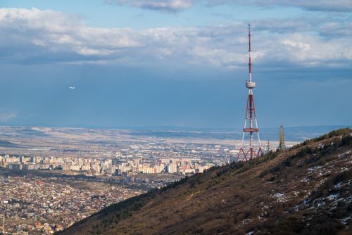 Free Aerial view of Tbilisi cityscape featuring the iconic Tbilisi TV Tower on a hilltop. Stock Photo