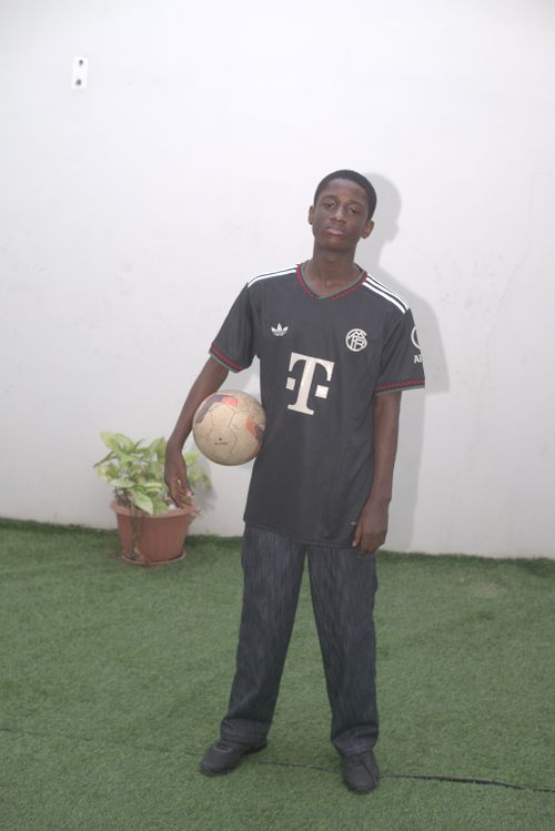 Free A young man poses with a soccer ball in a backyard in Abuja, Nigeria, wearing a black sports jersey. Stock Photo