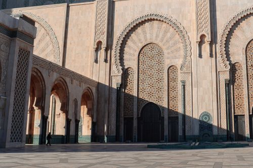 Free Stunning facade of a Moroccan mosque with intricate designs and warm sunlight casting shadows. Stock Photo
