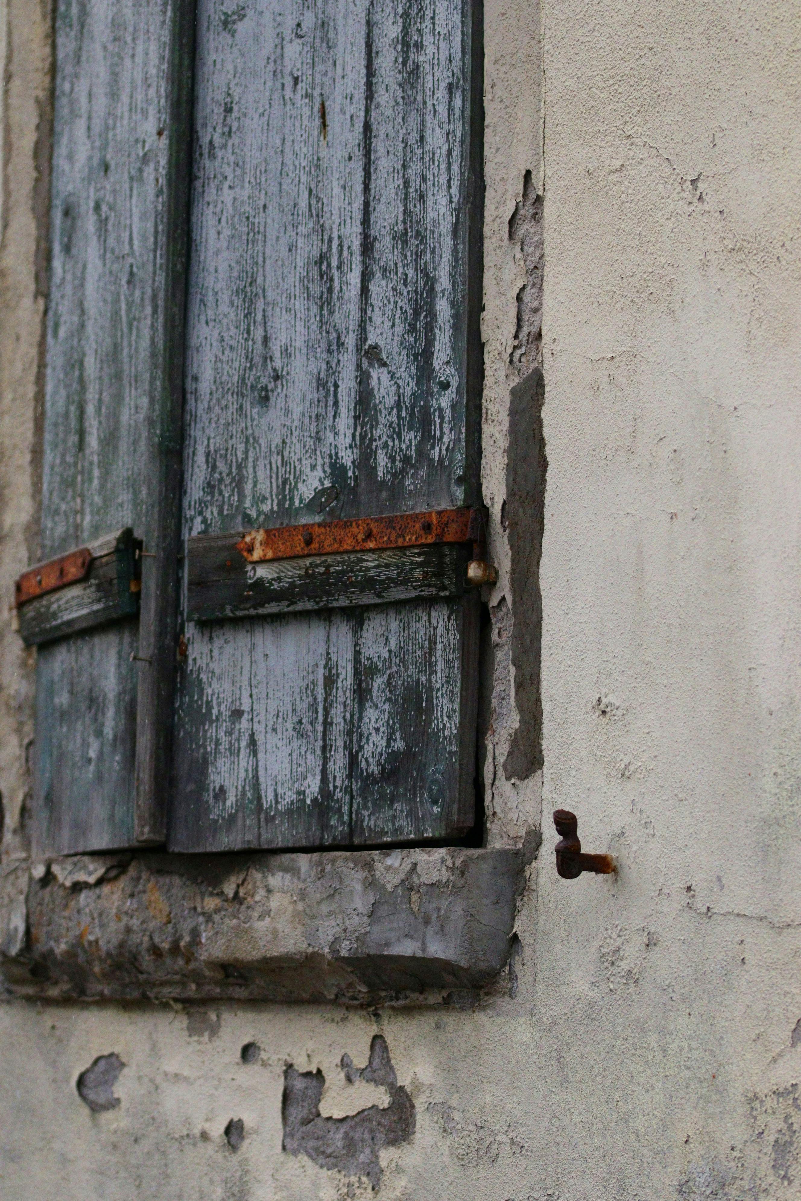 Free Rustic wooden shutters on a weathered wall exuding vintage charm. Stock Photo