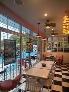 A retro diner with vintage decor, checkered floor, and classic posters under warm lighting.