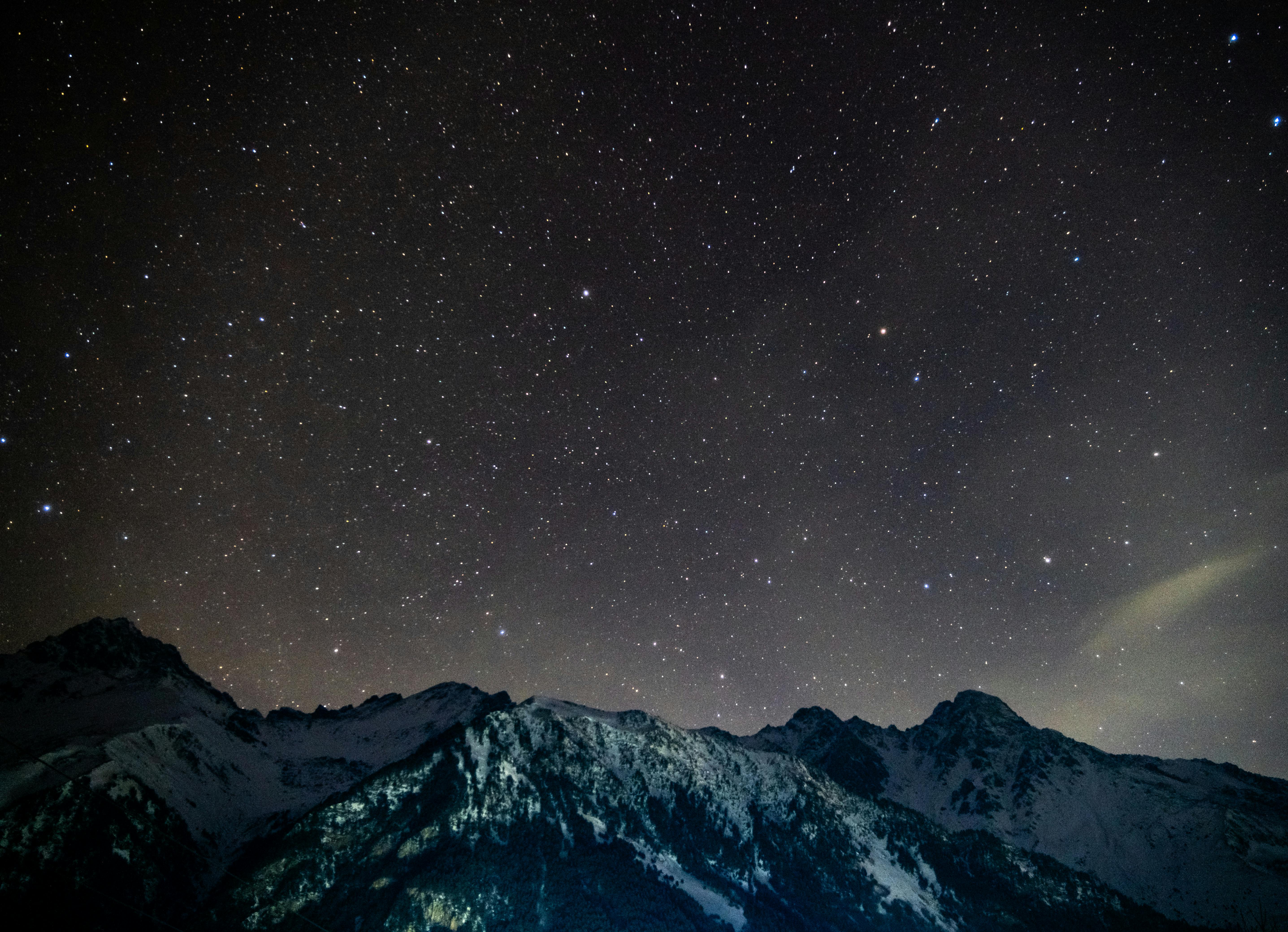 Δωρεάν Μια εκπληκτική θέα του έναστρου νυχτερινού ουρανού πάνω από τα χιονισμένα βουνά κάτω από τη σκοτεινή νύχτα. Φωτογραφία από στοκ φωτογραφιών