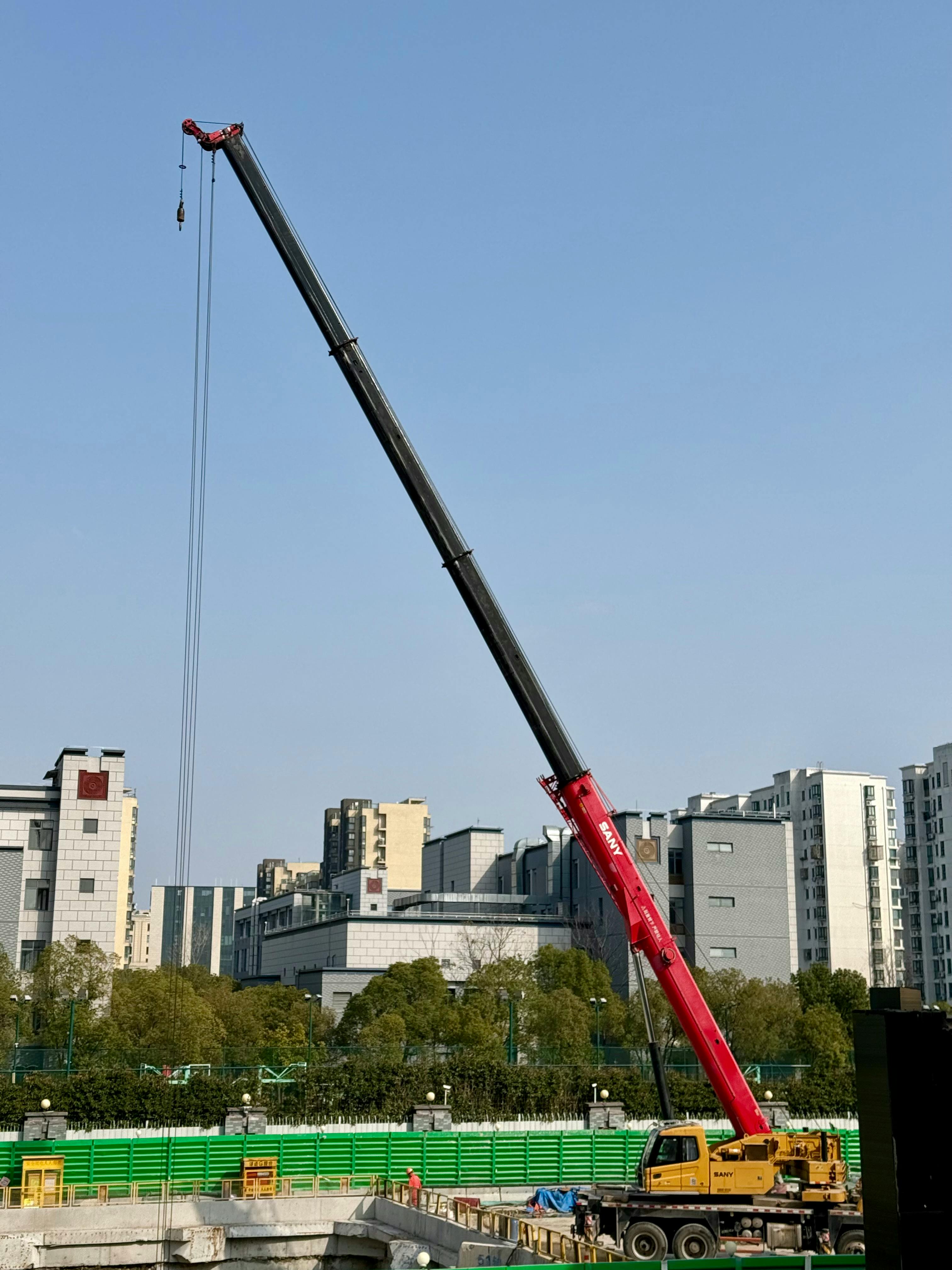 Gratis Un'imponente gru rossa in un cantiere edile a Shanghai, sullo sfondo di un cielo azzurro e limpido. Foto a disposizione