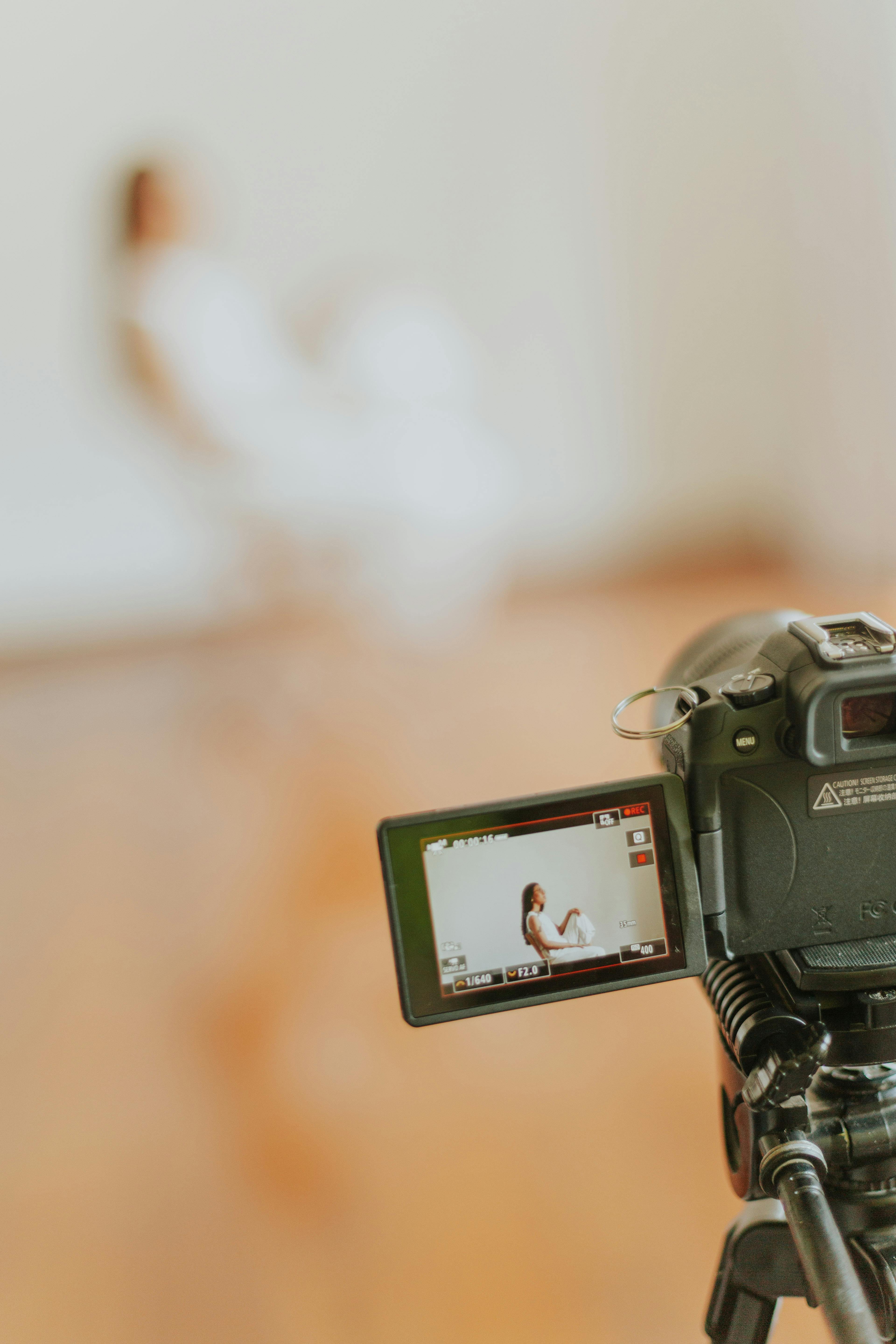 Gratis La telecamera inquadra una figura sfocata in un ambiente interno, mettendo a fuoco l'attrezzatura di ripresa. Foto a disposizione