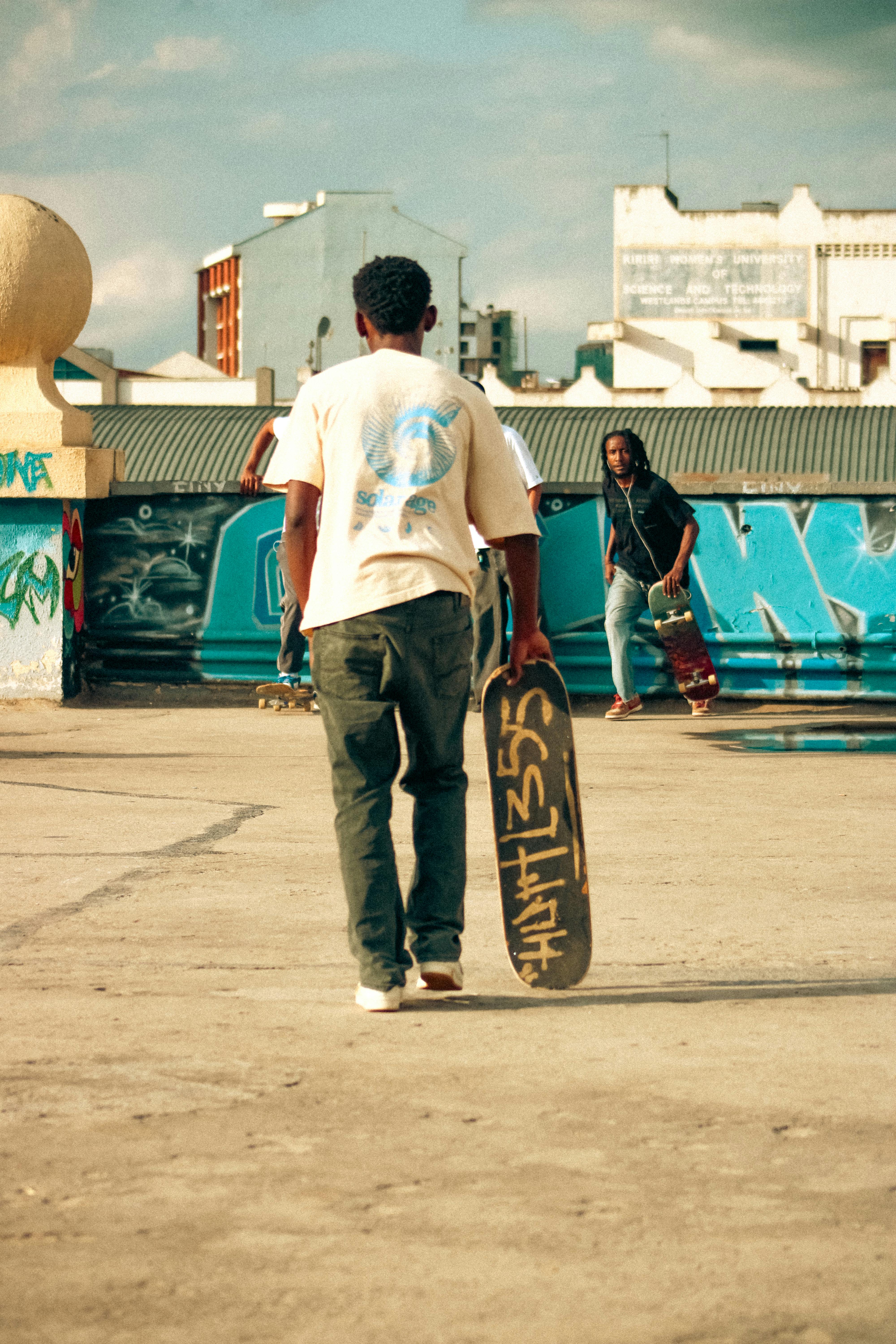 Kostenlos Zwei Männer vergnügen sich beim Skateboarden auf einem Dach in einer urbanen Umgebung mit Graffiti. Stock-Foto