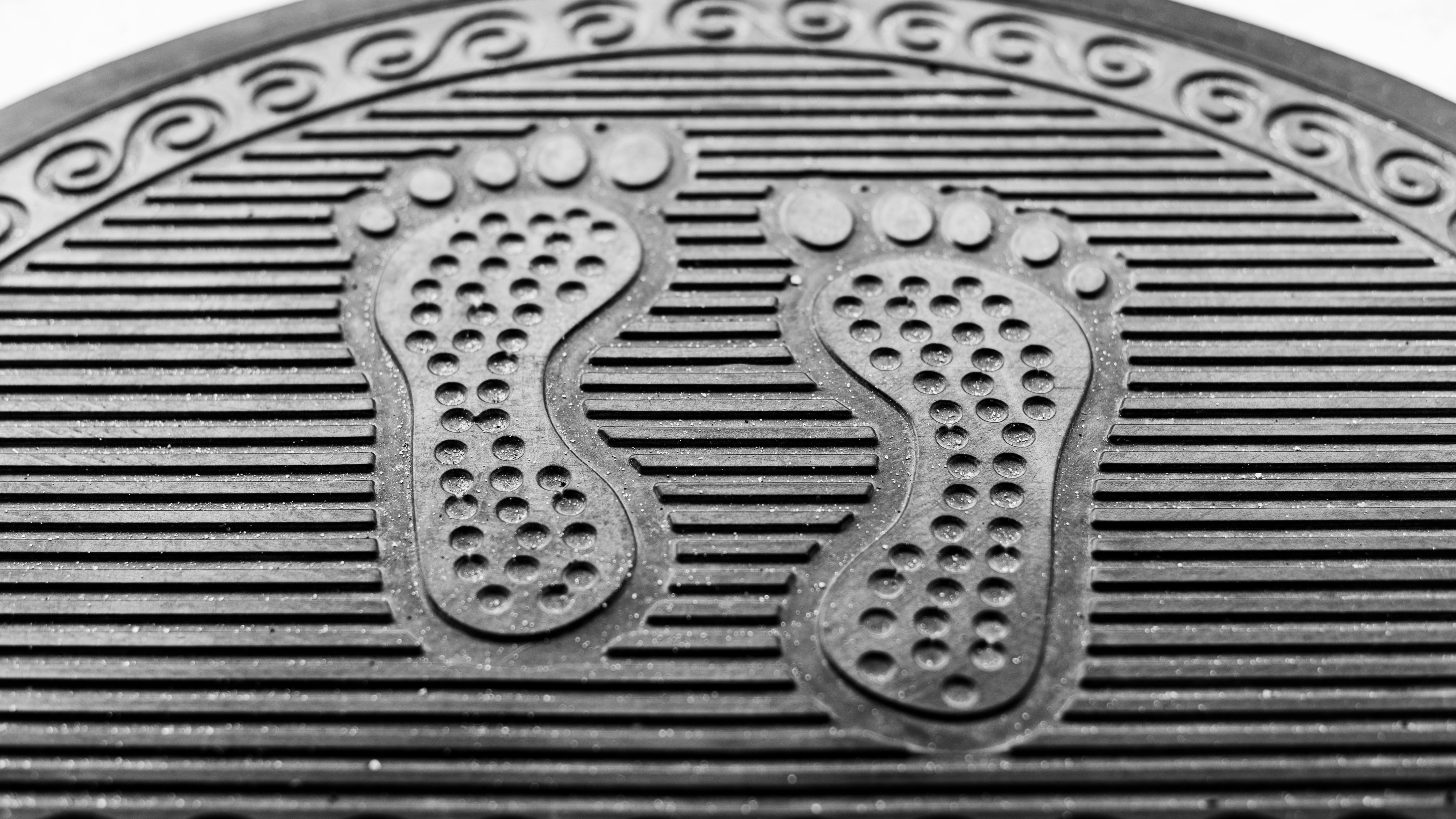 Gratuit Gros plan sur un paillasson en caoutchouc noir texturé à motif d'empreintes de pas. Idéal pour la maison ou le bureau. Photos