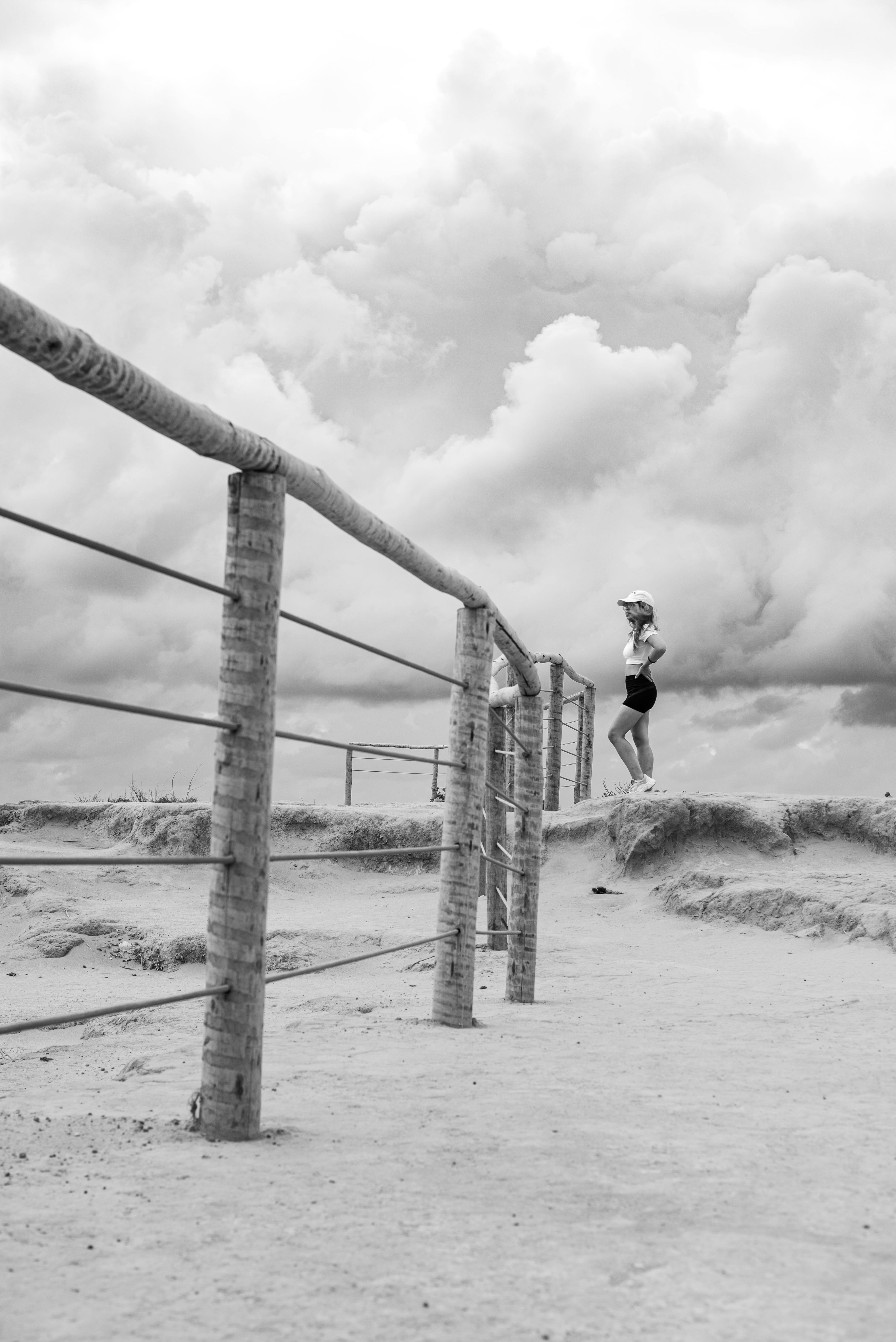 無料 ブラジルのナタールにある砂浜に立つ女性を、ドラマチックな雲の下に捉えた白黒写真。 写真素材