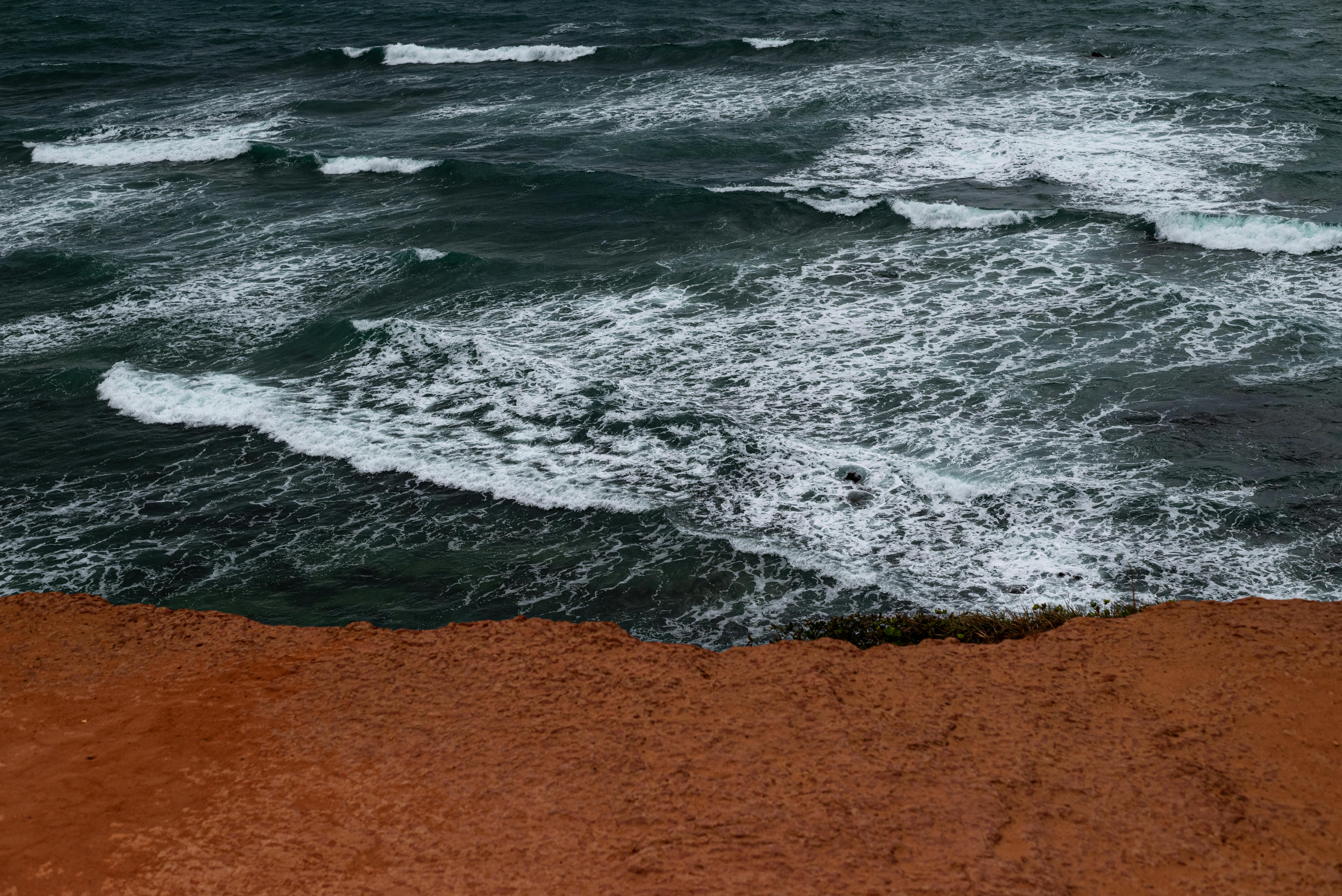 Gratis Onde impetuose si infrangono contro scogliere rosse su una costa spettacolare a Natal, in Brasile. La potenza della natura catturata in un'immagine magistrale. Foto a disposizione
