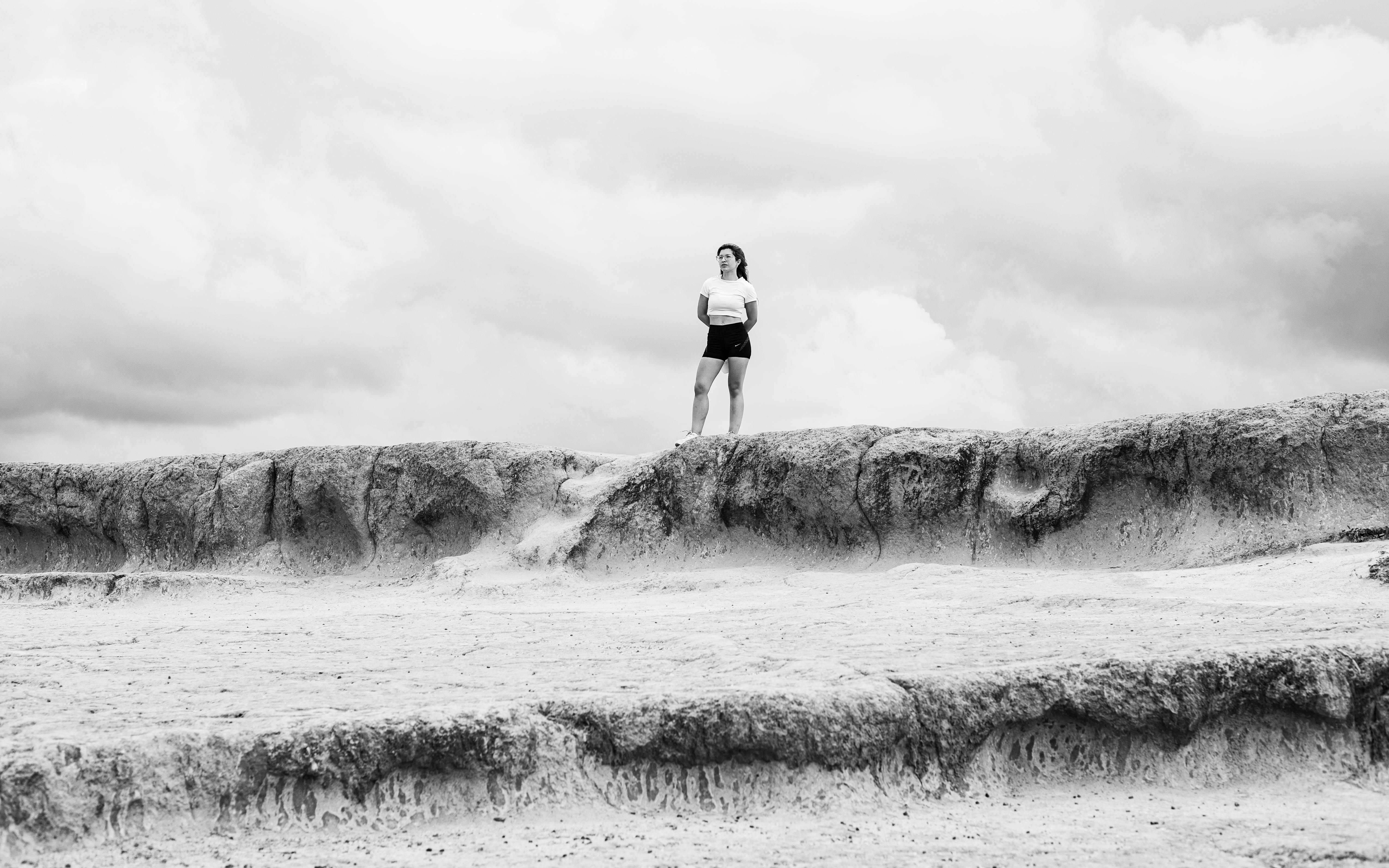Free A woman standing on rugged terrain under a dramatic cloudy sky in Natal, Brazil. Stock Photo