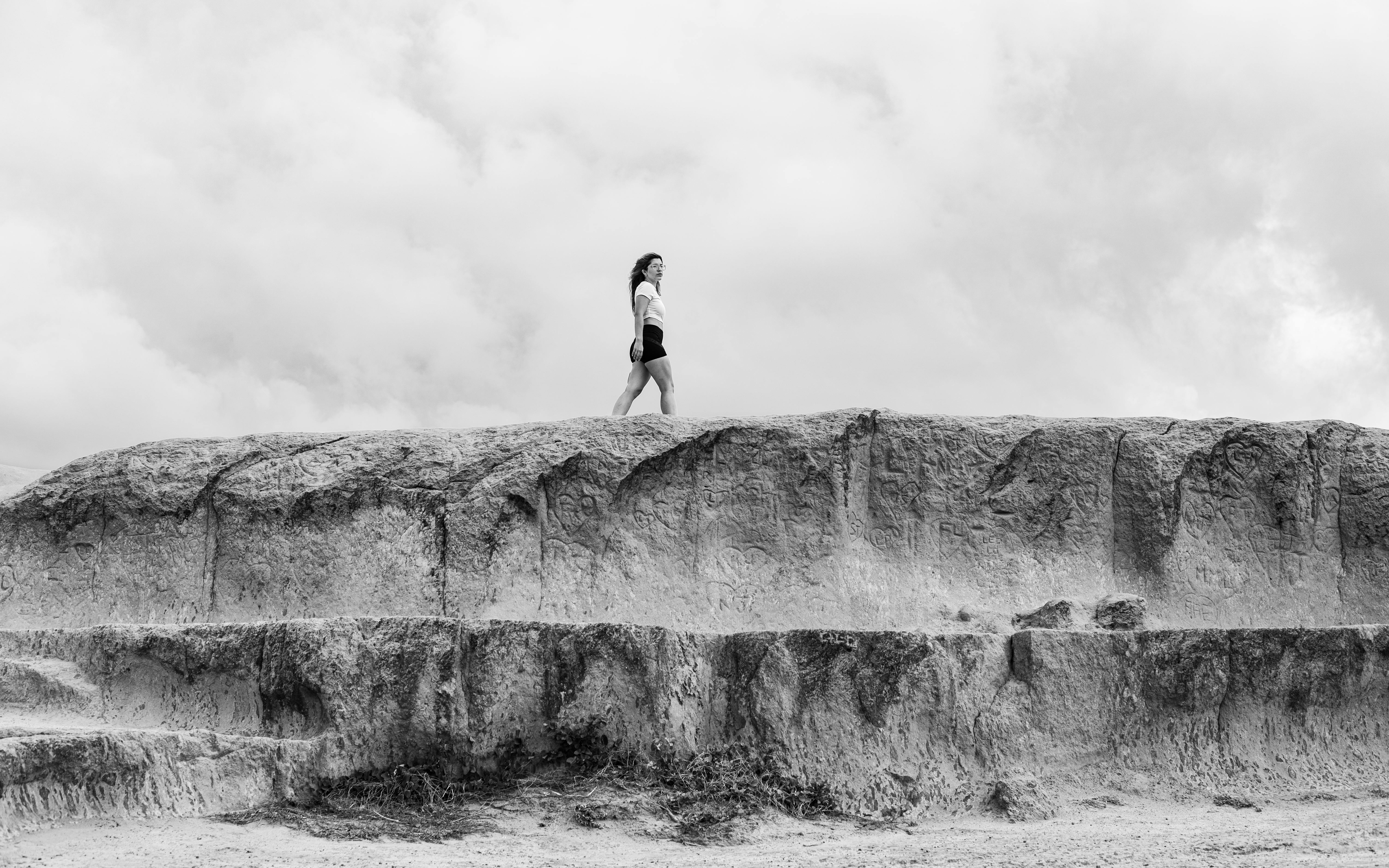 gratis Een vrouw loopt alleen over een rotsachtige heuvel onder een bewolkte hemel in Natal, Brazilië. Stockfoto