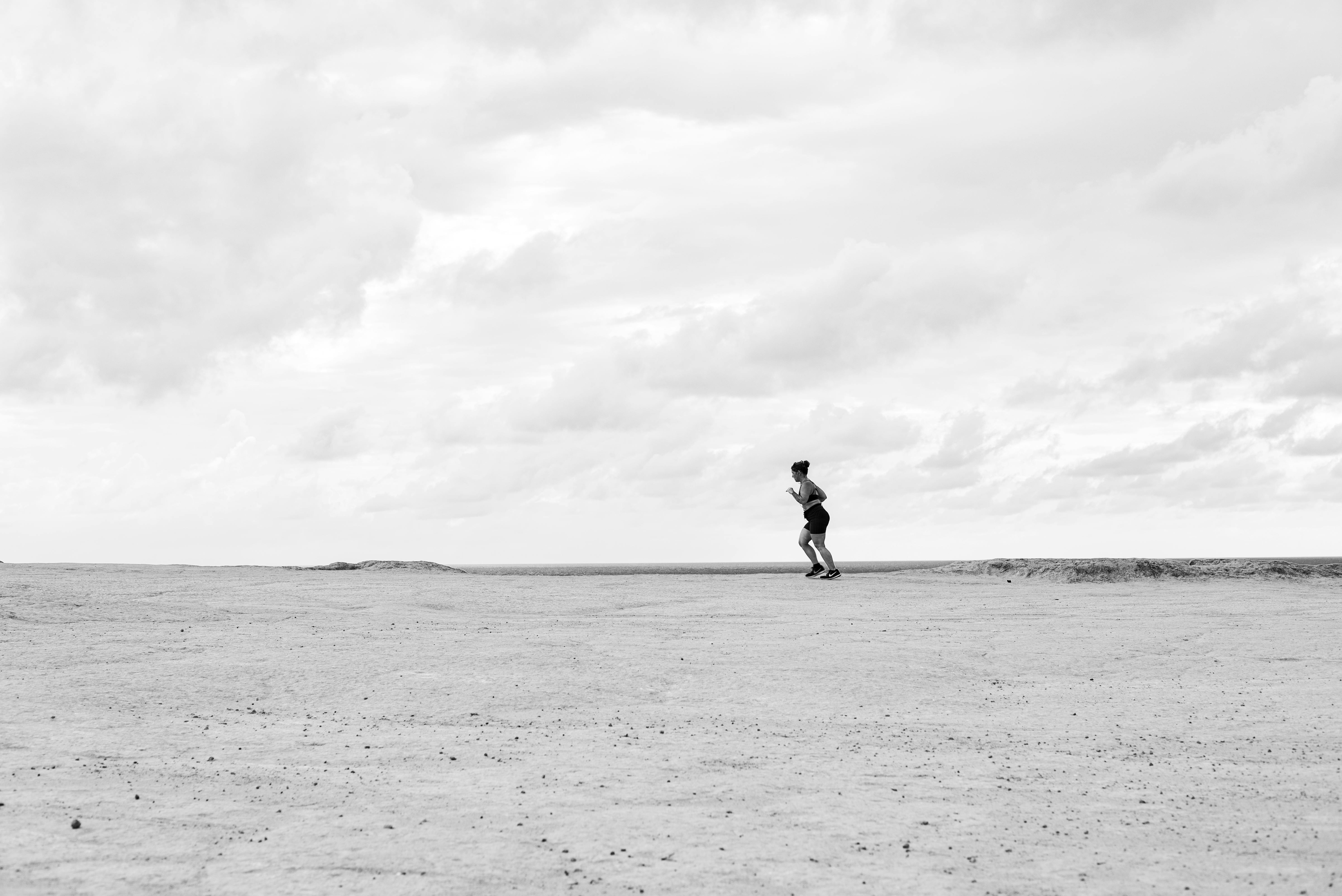 Gratuit Un coureur solitaire sur un vaste terrain ouvert sous un ciel nuageux, photographié à Natal, au Brésil. Photos