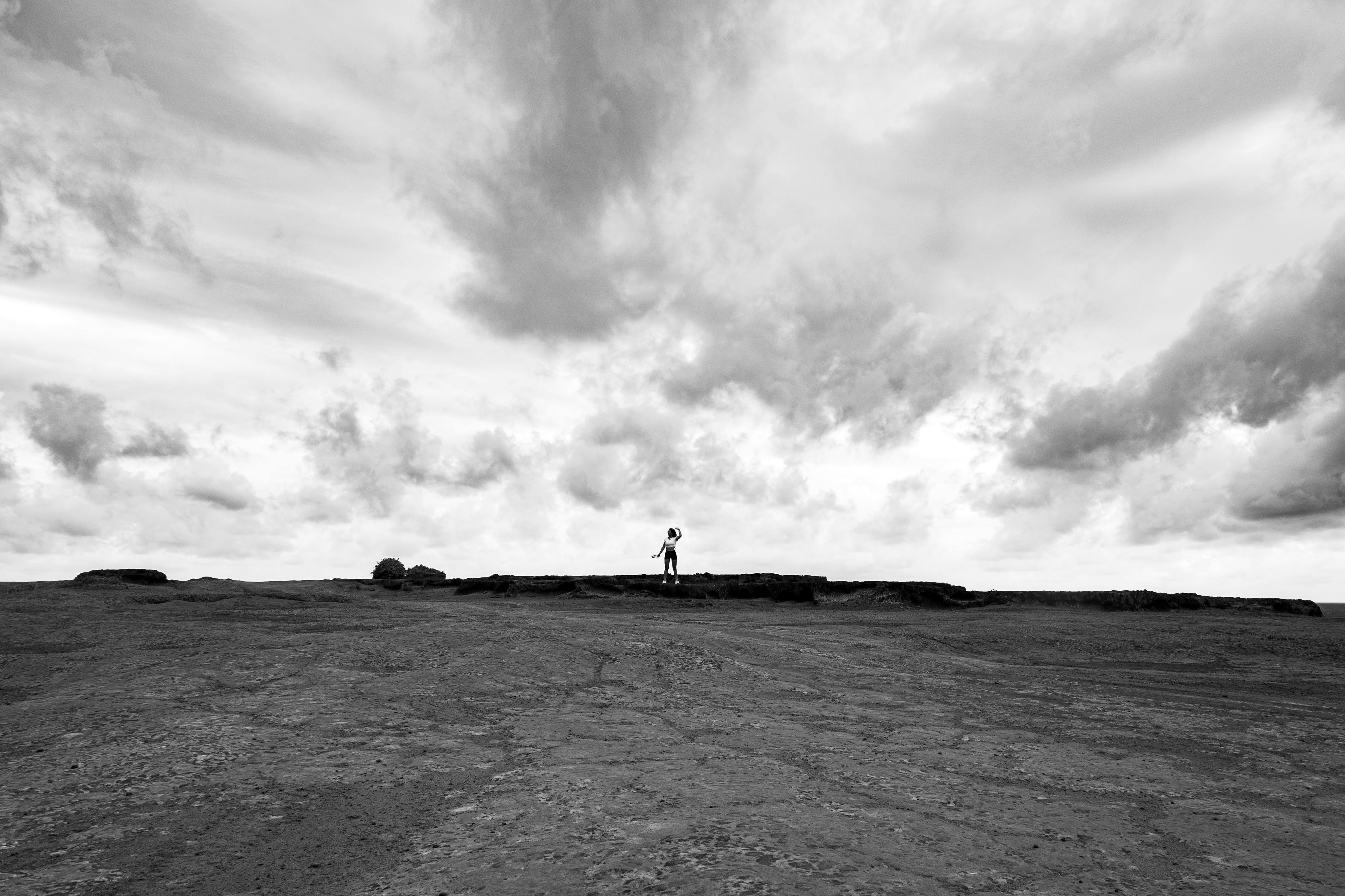 Free Person stands on rocky terrain under a dramatic cloudy sky in Natal, Brazil. Stock Photo