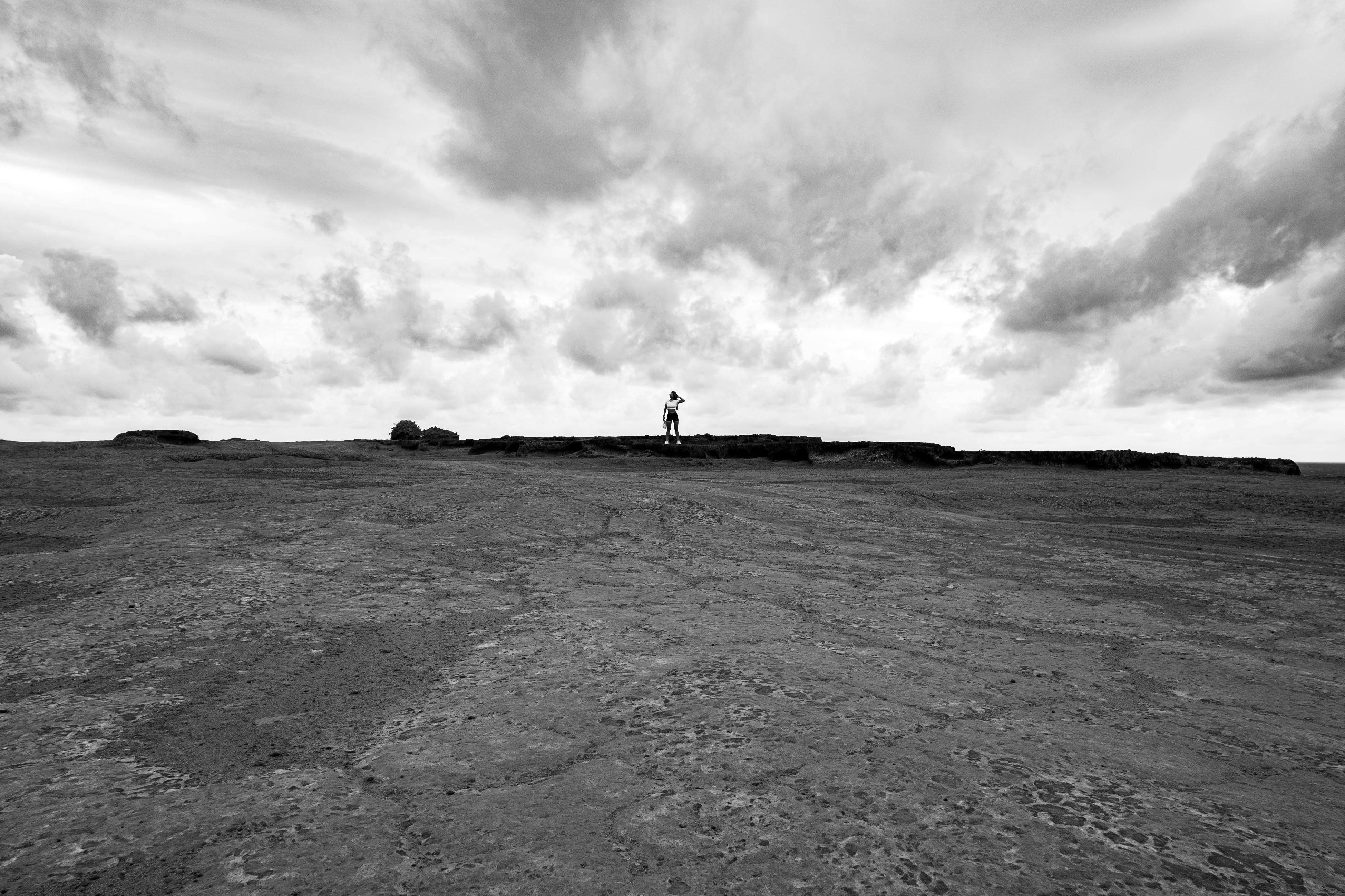 De franc Una figura solitària es troba sobre un extens terreny rocós sota núvols espectaculars a Natal, Brasil. Foto d'estoc