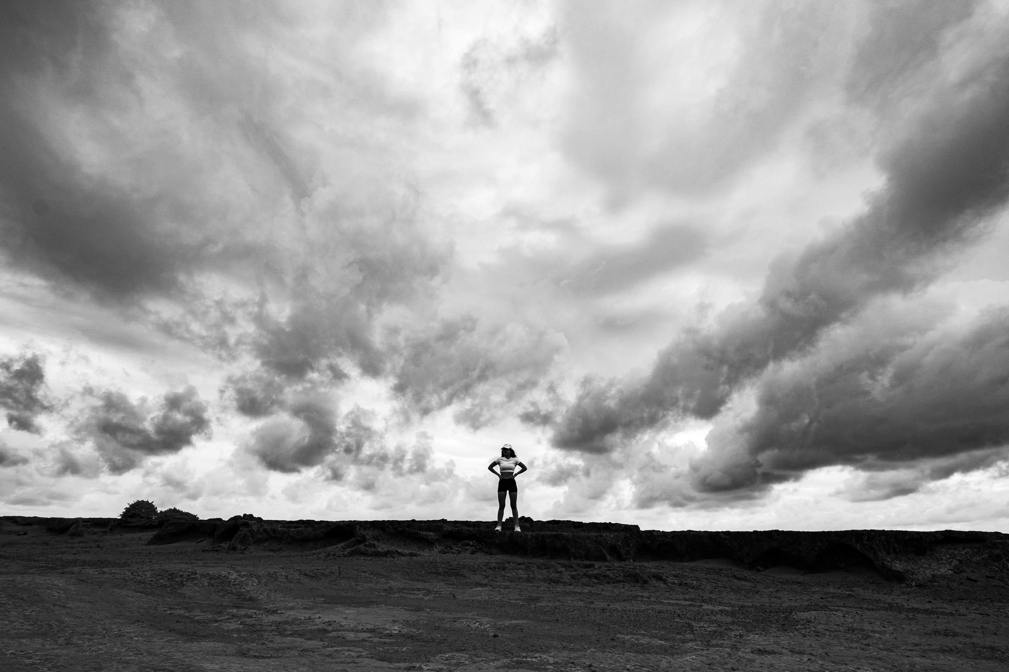 Gratis Una persona se yergue con valentía bajo espectaculares formaciones de nubes, simbolizando la introspección, en Natal, Brasil. Foto de stock
