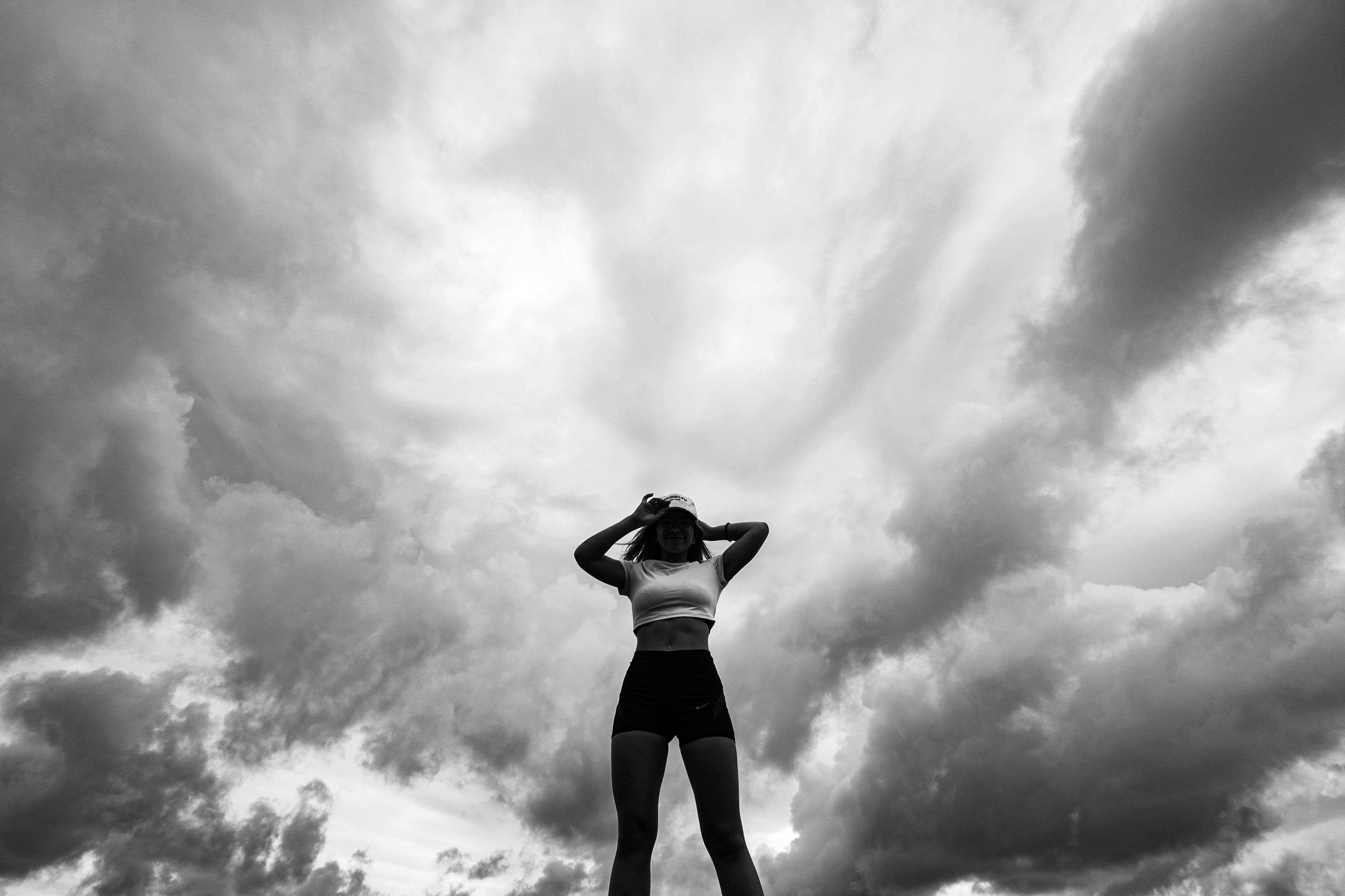 Gratis Silhouette in bianco e nero di una donna in piedi sotto un cielo nuvoloso e suggestivo a Natal, in Brasile. Foto a disposizione