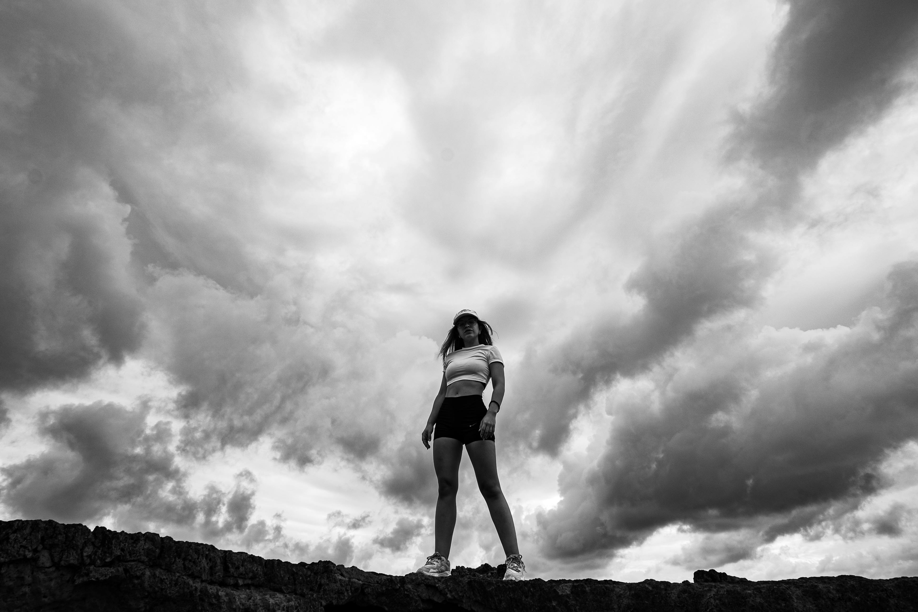 Gratis Immagine in bianco e nero di una donna in piedi con aria sicura contro un cielo nuvoloso e suggestivo nel Rio Grande do Norte. Foto a disposizione