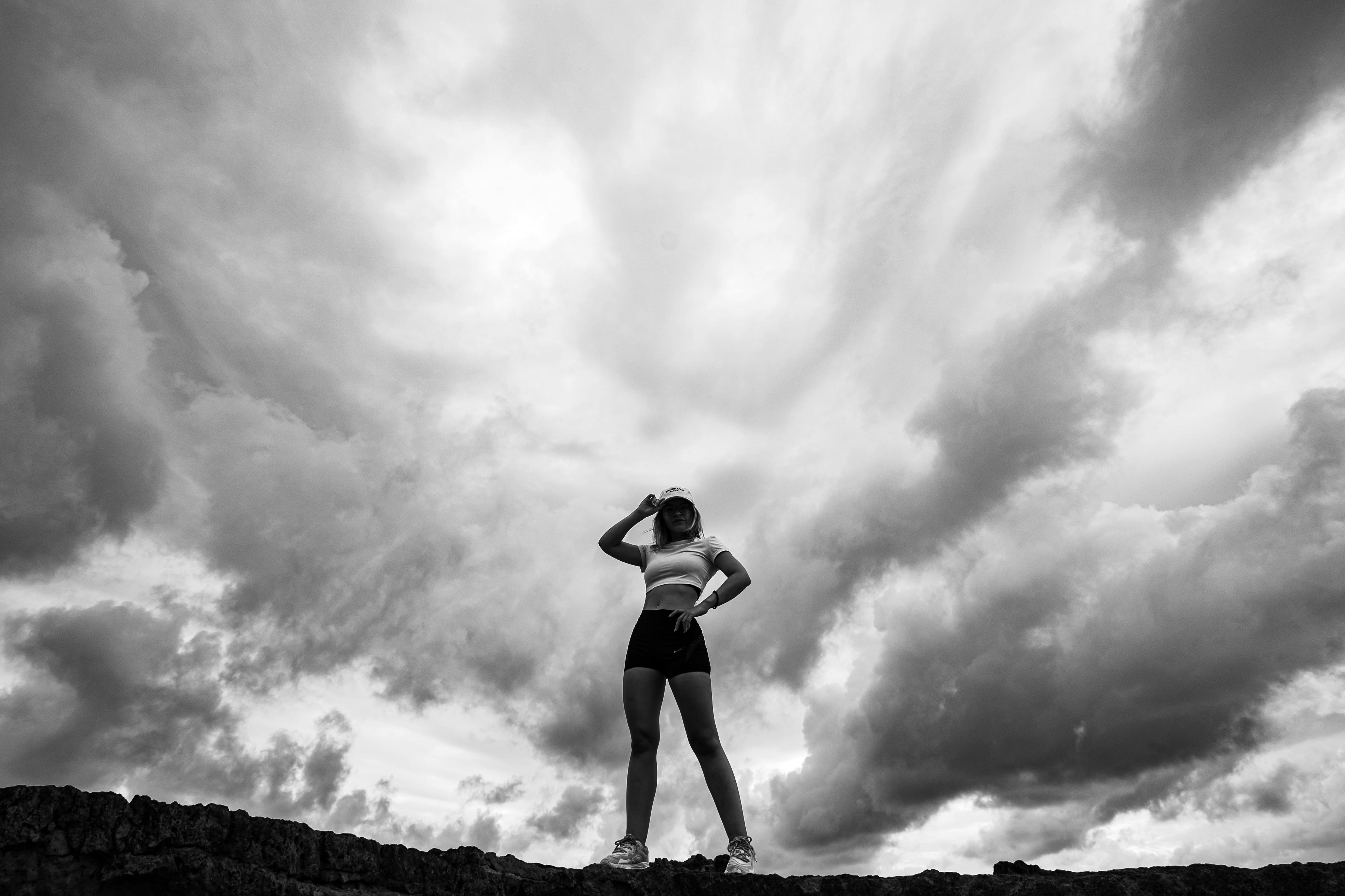grátis Silhueta de uma mulher em pé, confiante, contra um céu nublado e dramático em Natal, Brasil. Foto profissional