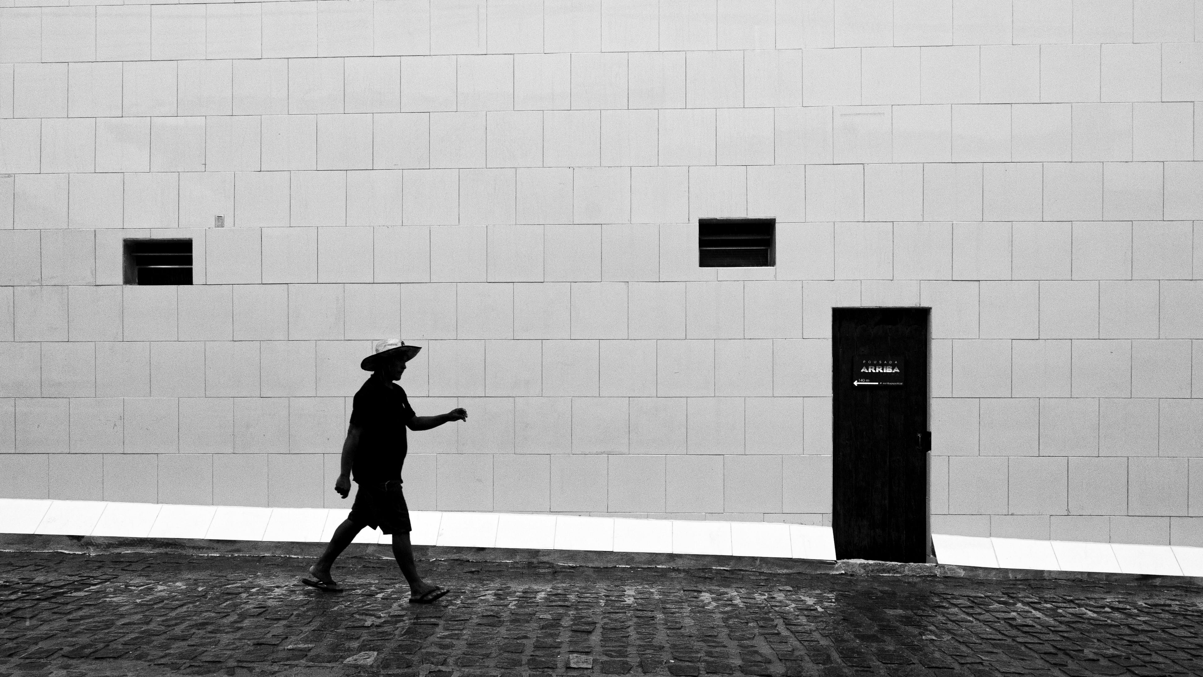 Free A man in silhouette walking past a textured wall in Natal, Brazil. Stock Photo
