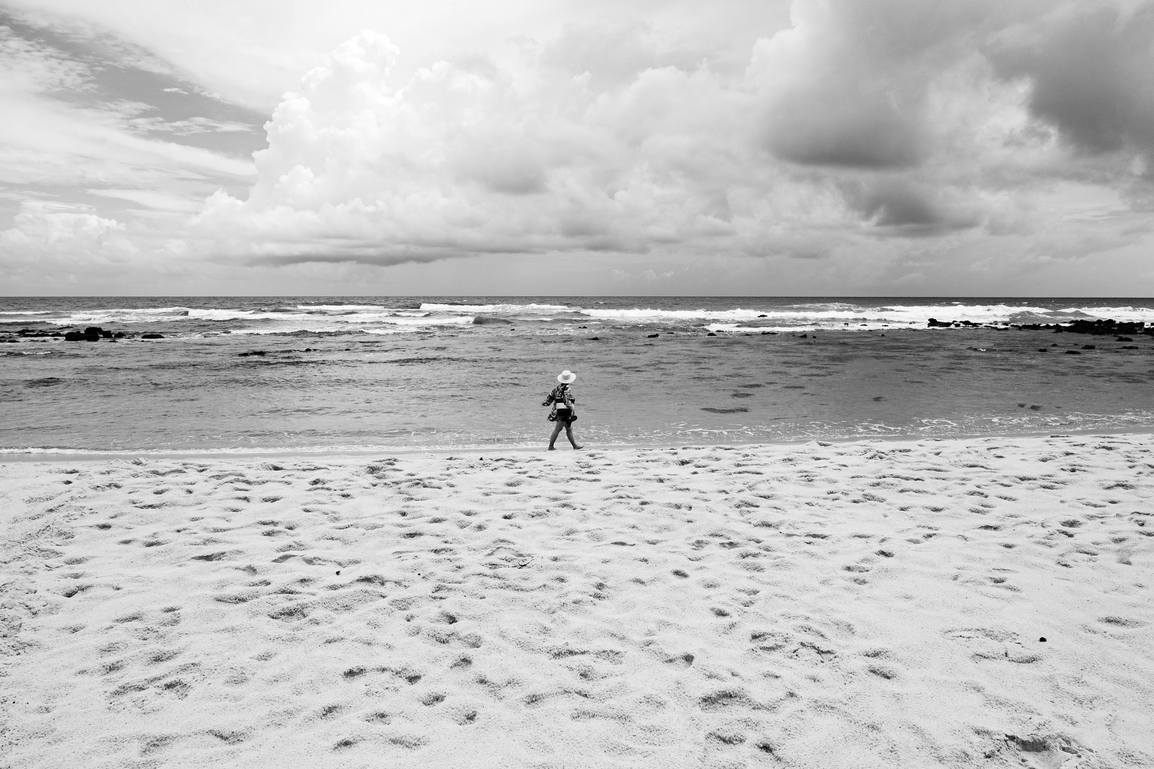 Gratuit Un enfant marche le long d'une plage de sable sous un ciel nuageux à Natal, au Brésil. Photos