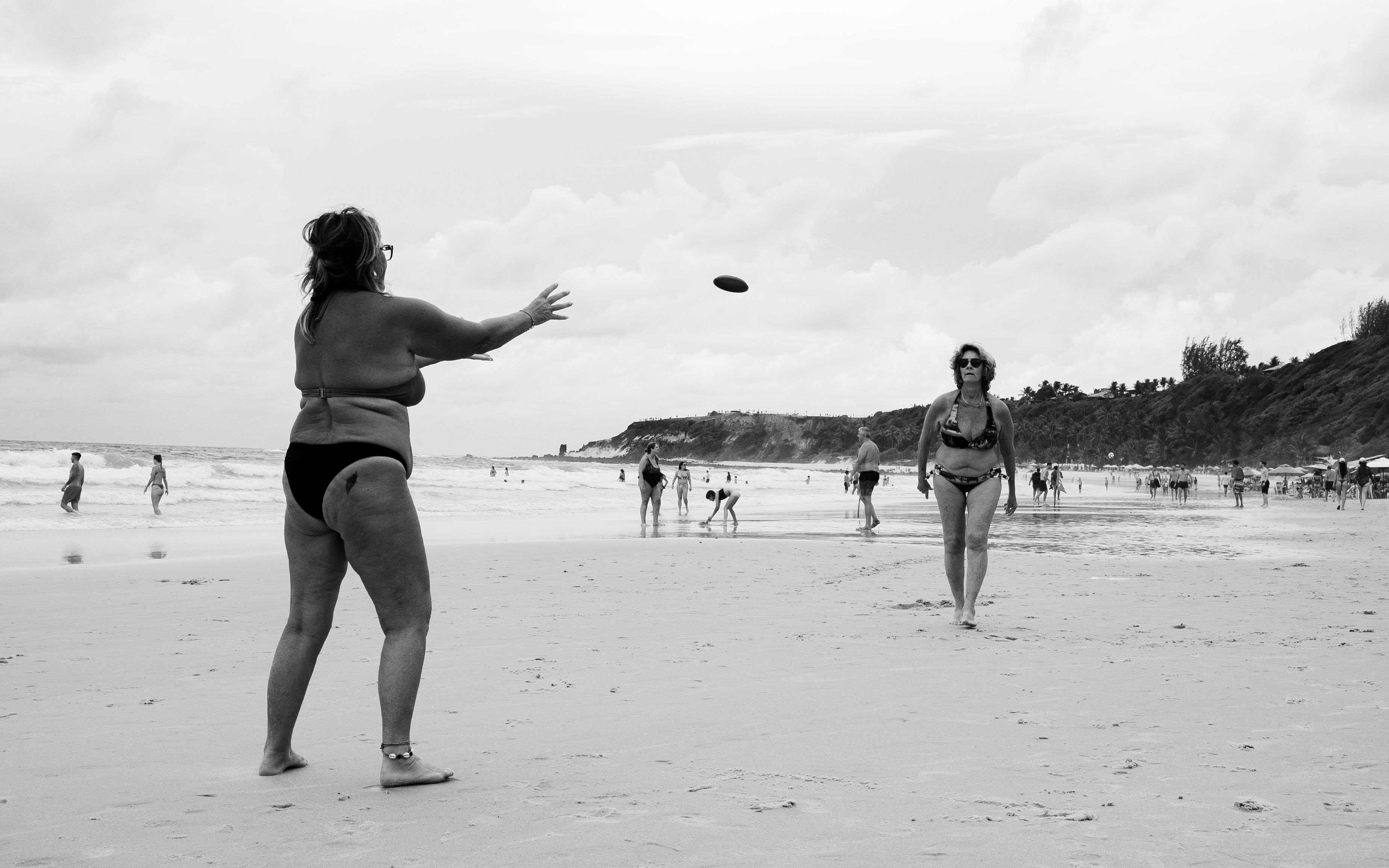Two women playing frisbee on a scenic Natal beach in Brazil, capturing leisure and enjoyment.
