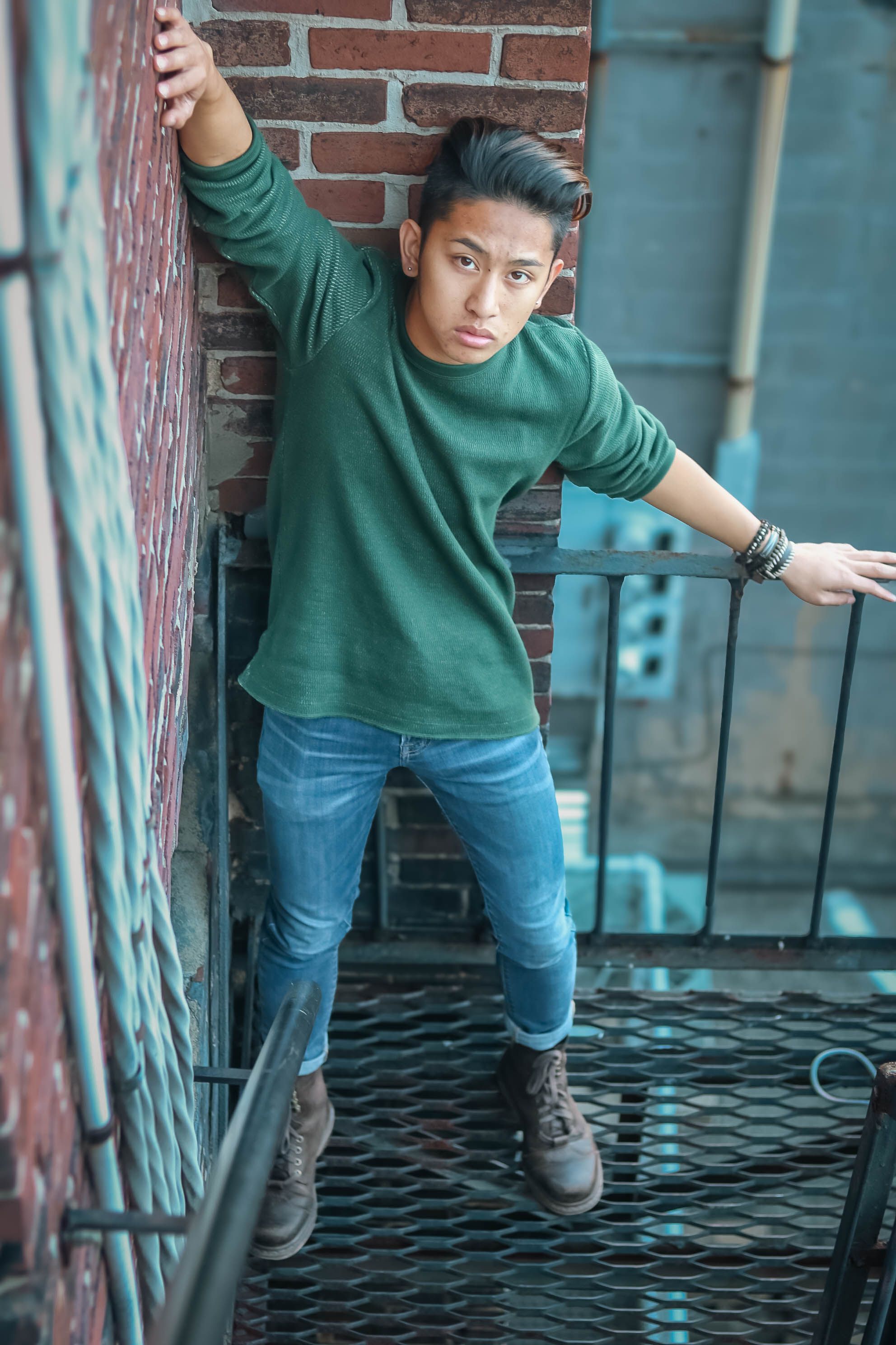 Teenager stands on a city fire escape, showcasing fashion and style in an urban setting.