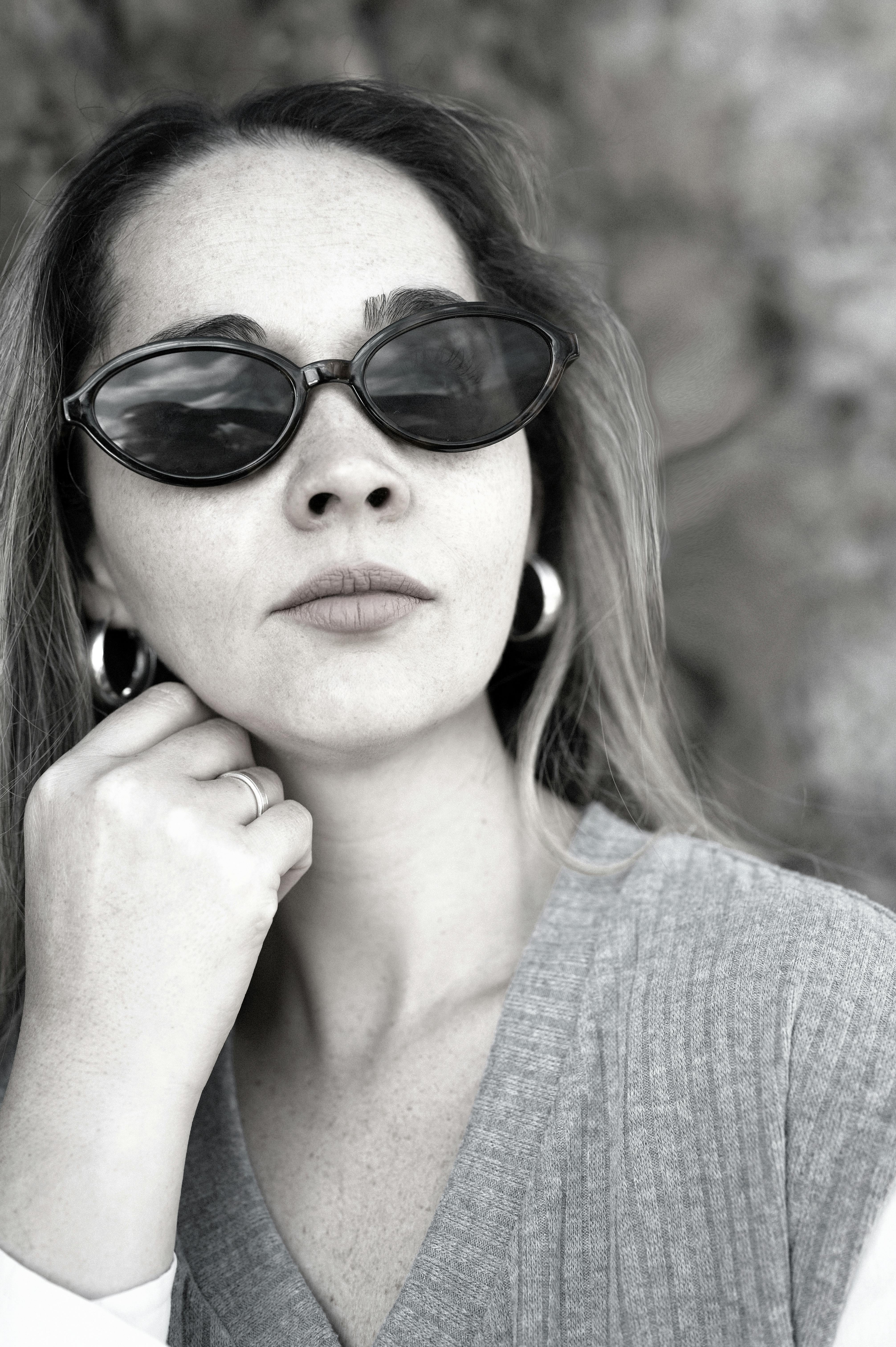 De franc Retrat elegant en blanc i negre d'una dona amb ulleres de sol i arracades. Foto d'estoc