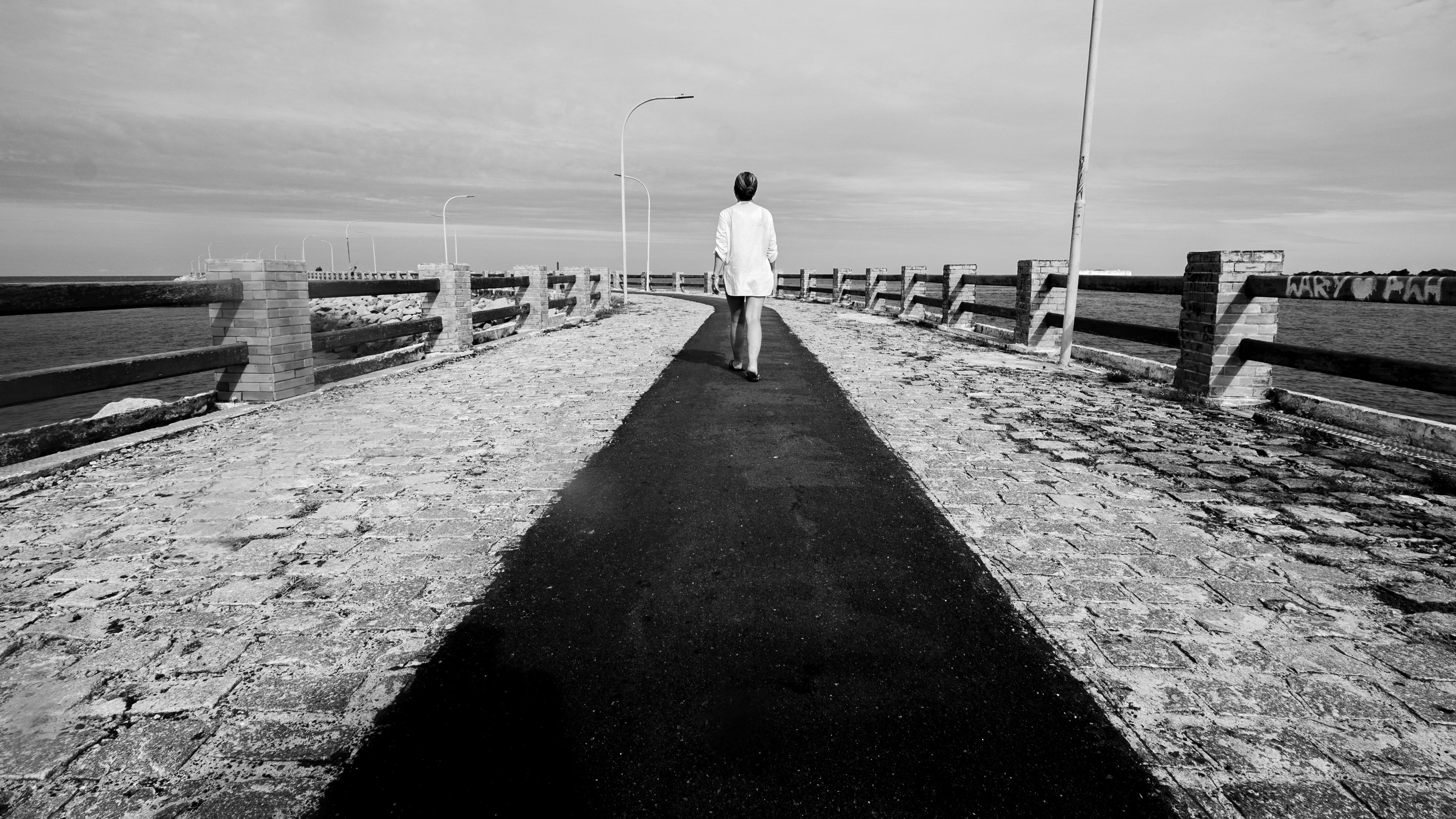 Gratis Una figura solitaria cammina su un ponte a Natal, in Brasile, immortalata in bianco e nero. Foto a disposizione