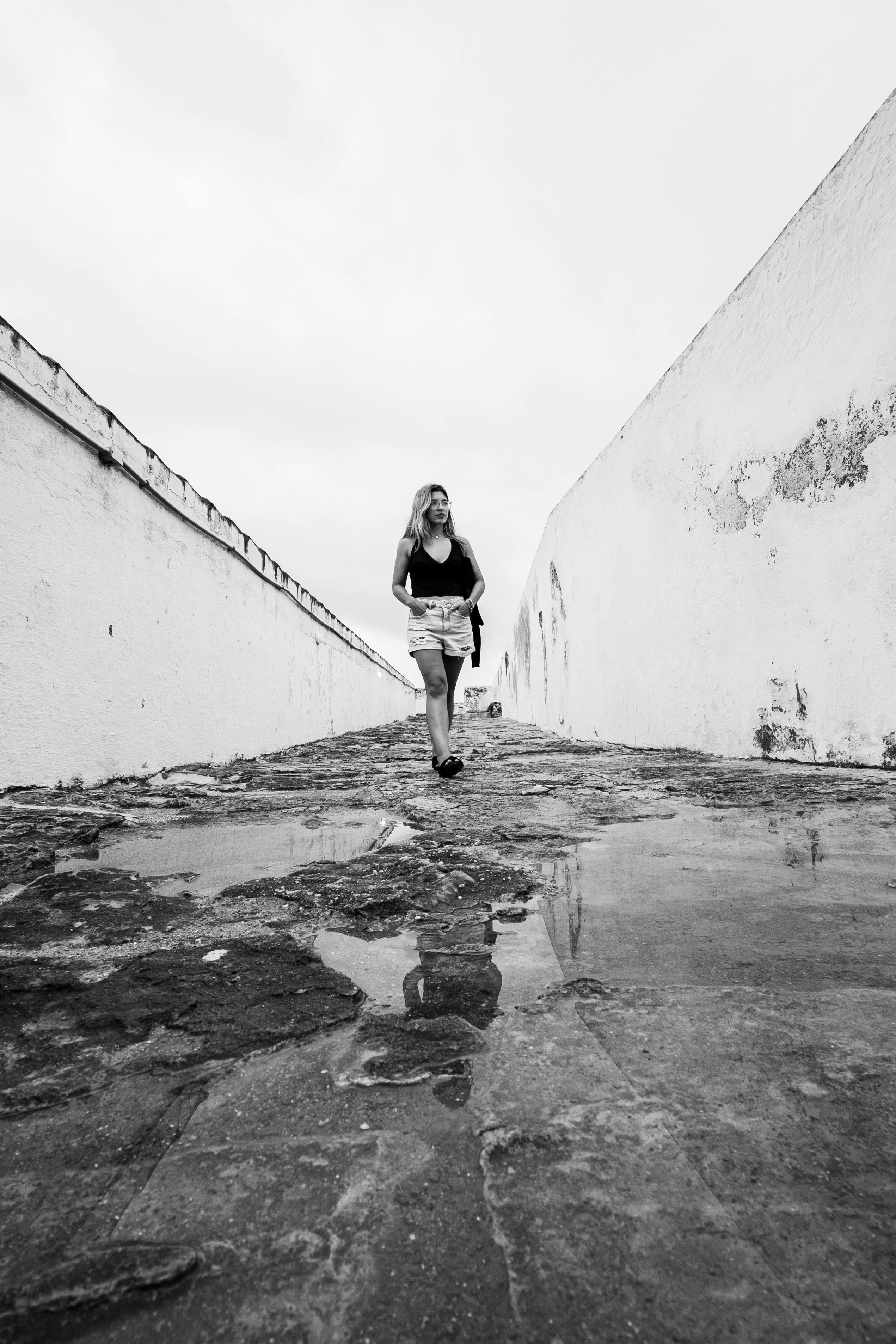 De franc Fotografia en blanc i negre d'una dona caminant per un carrer estret a Natal, Brasil. Foto d'estoc