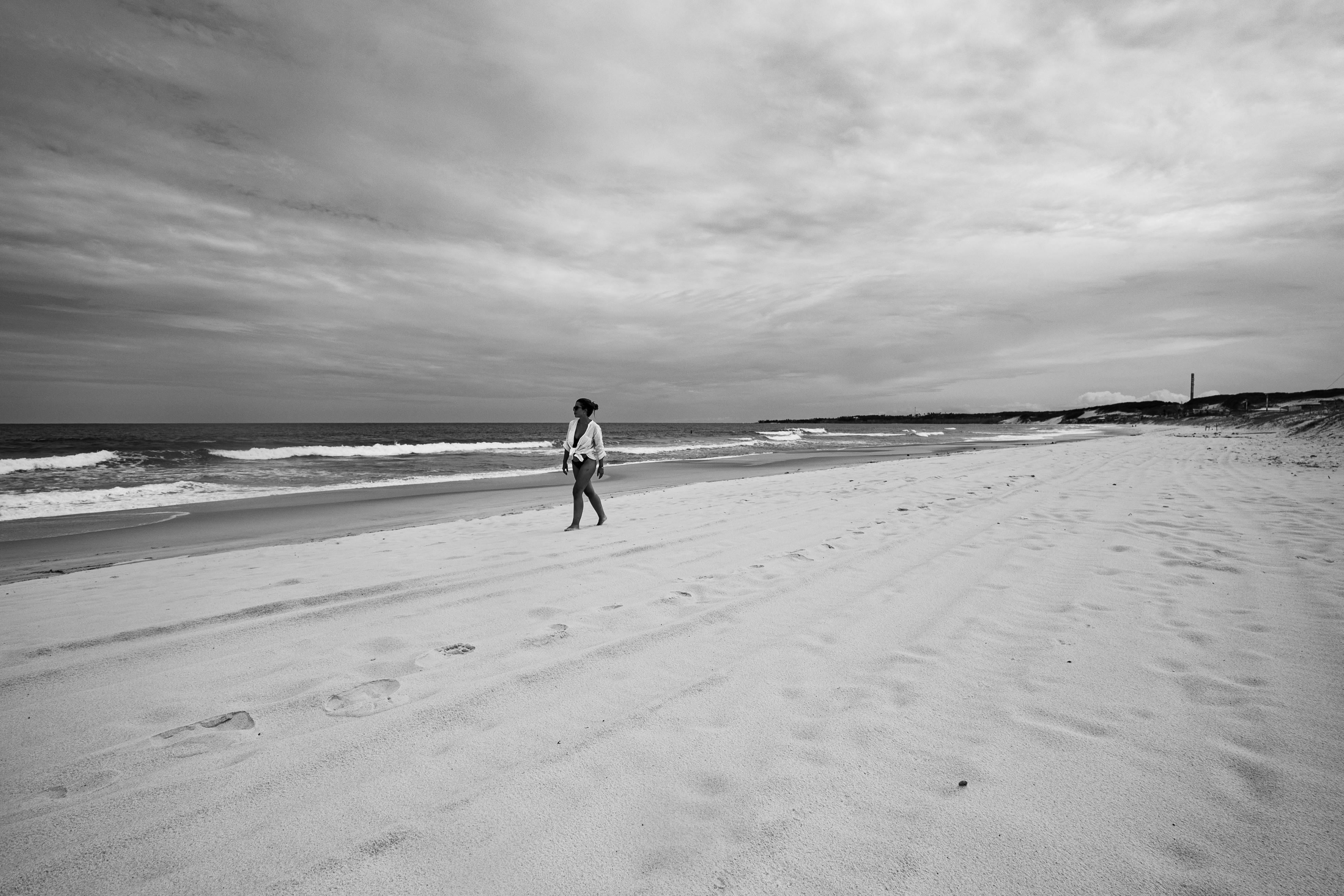 Gratis Foto in bianco e nero di una persona che cammina da sola sulla spiaggia di Genipabu, a Natal, in Brasile. Foto a disposizione
