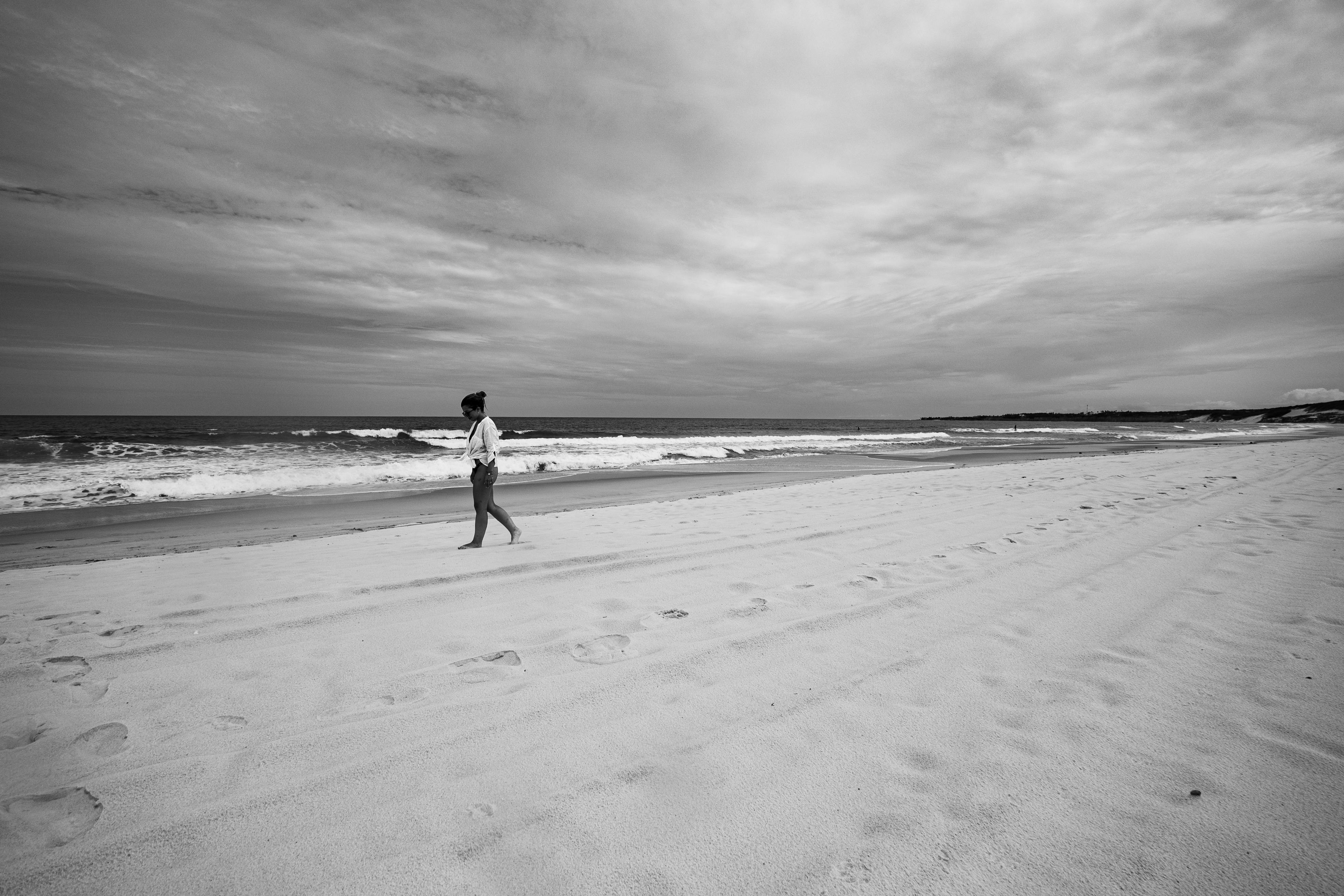 Bezpłatne Osoba spacerująca po spokojnej plaży w Natalu w Brazylii, uchwycona na czarno-białym zdjęciu. Zdjęcie z galerii
